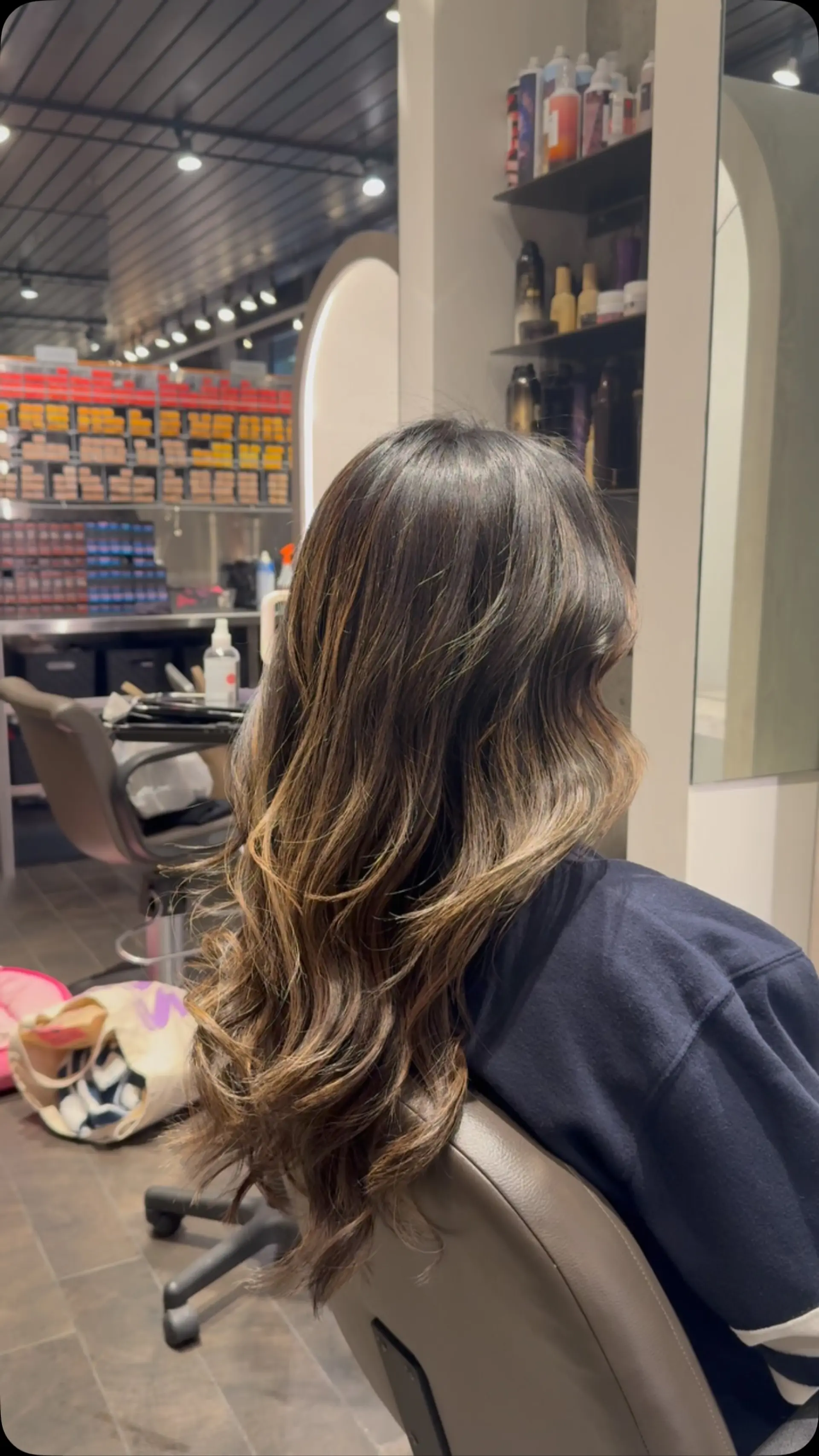 Long dark brown hair styled in soft, glossy waves with blended warm caramel highlights for added depth and movement. 1