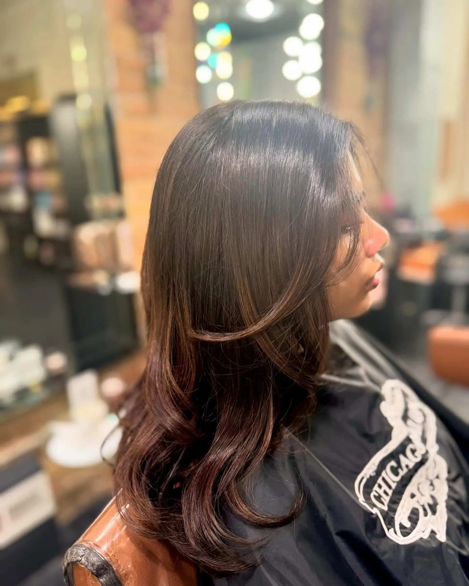 A sleek, dark brunette layered style featuring face-framing pieces and smooth, voluminous curved ends. 1