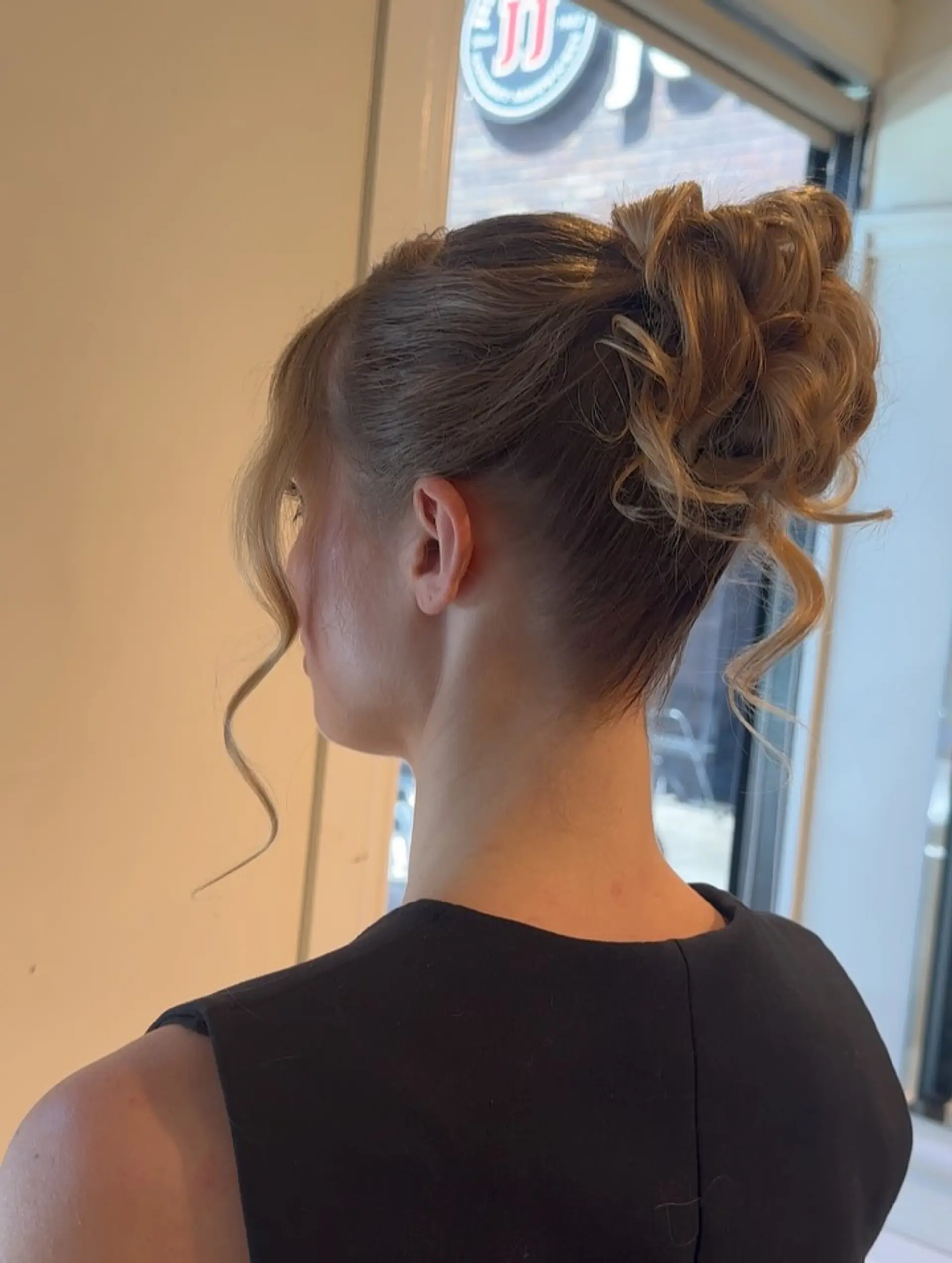 An elegant textured updo gathered into a curly high bun with soft, curled tendrils framing the face. 1