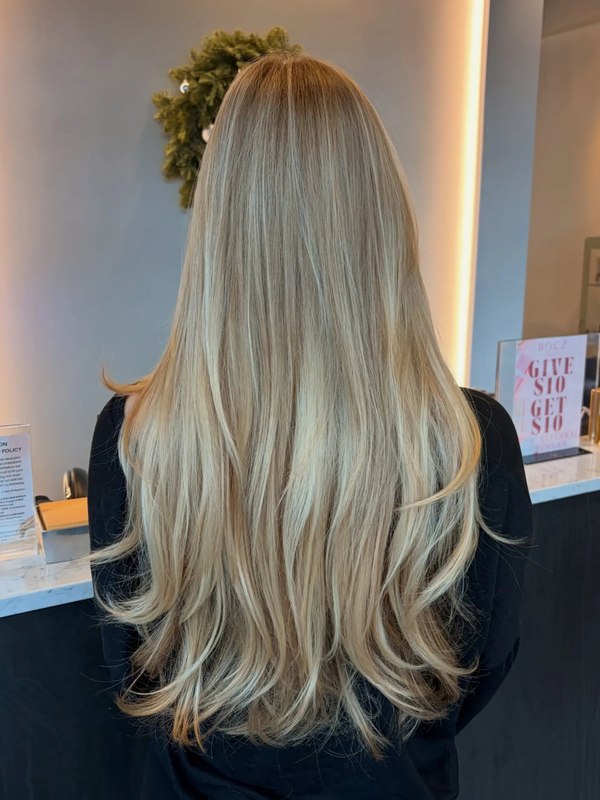 Long, flowing blonde hair styled with subtle flipped ends and soft interior layers, showcasing seamless dimensional balayage highlights. 1