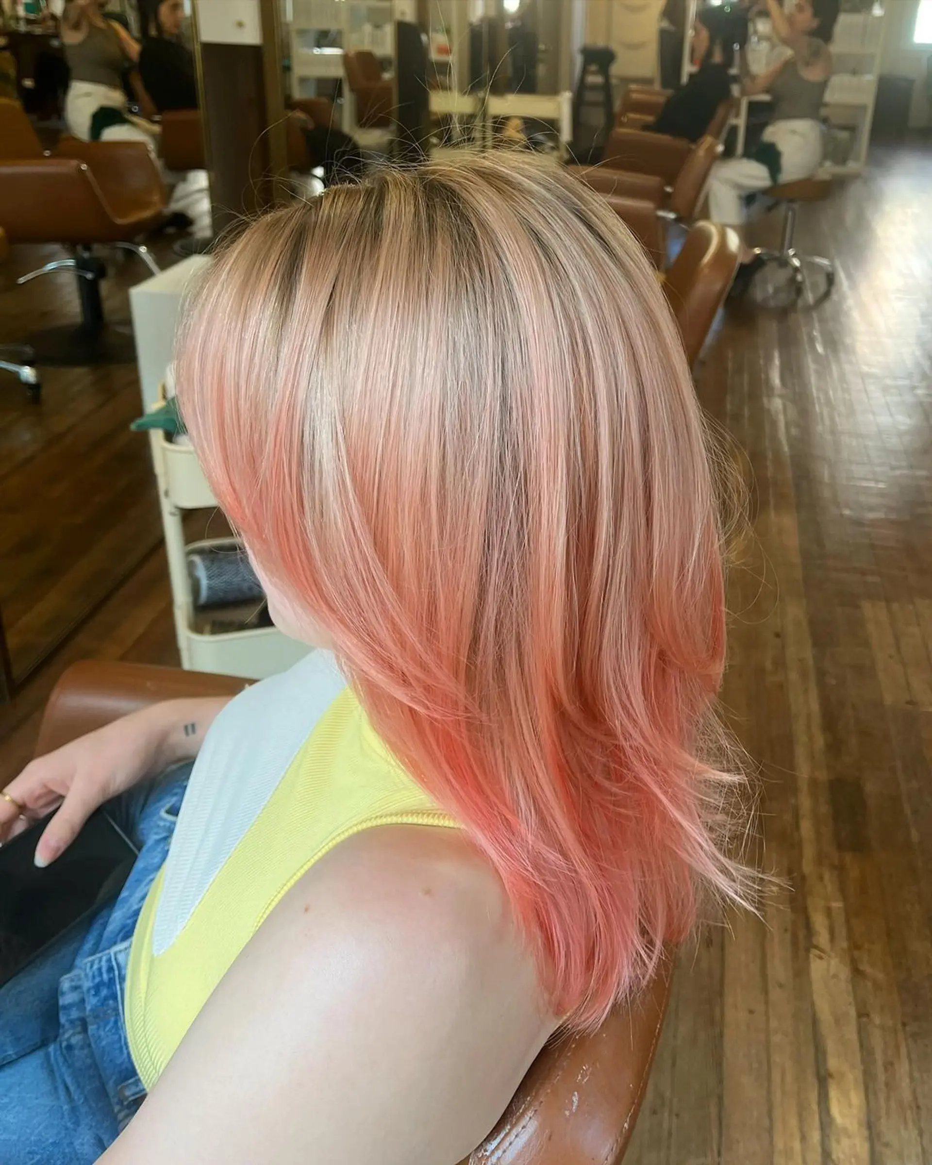 A medium-length wavy hairstyle with layered cuts and face-framing bangs, featuring strawberry blonde and peach colors. 4