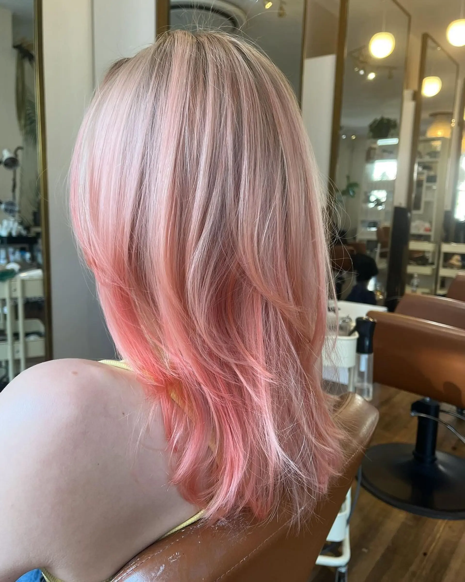 A medium-length wavy hairstyle with layered cuts and face-framing bangs, featuring strawberry blonde and peach colors. 5