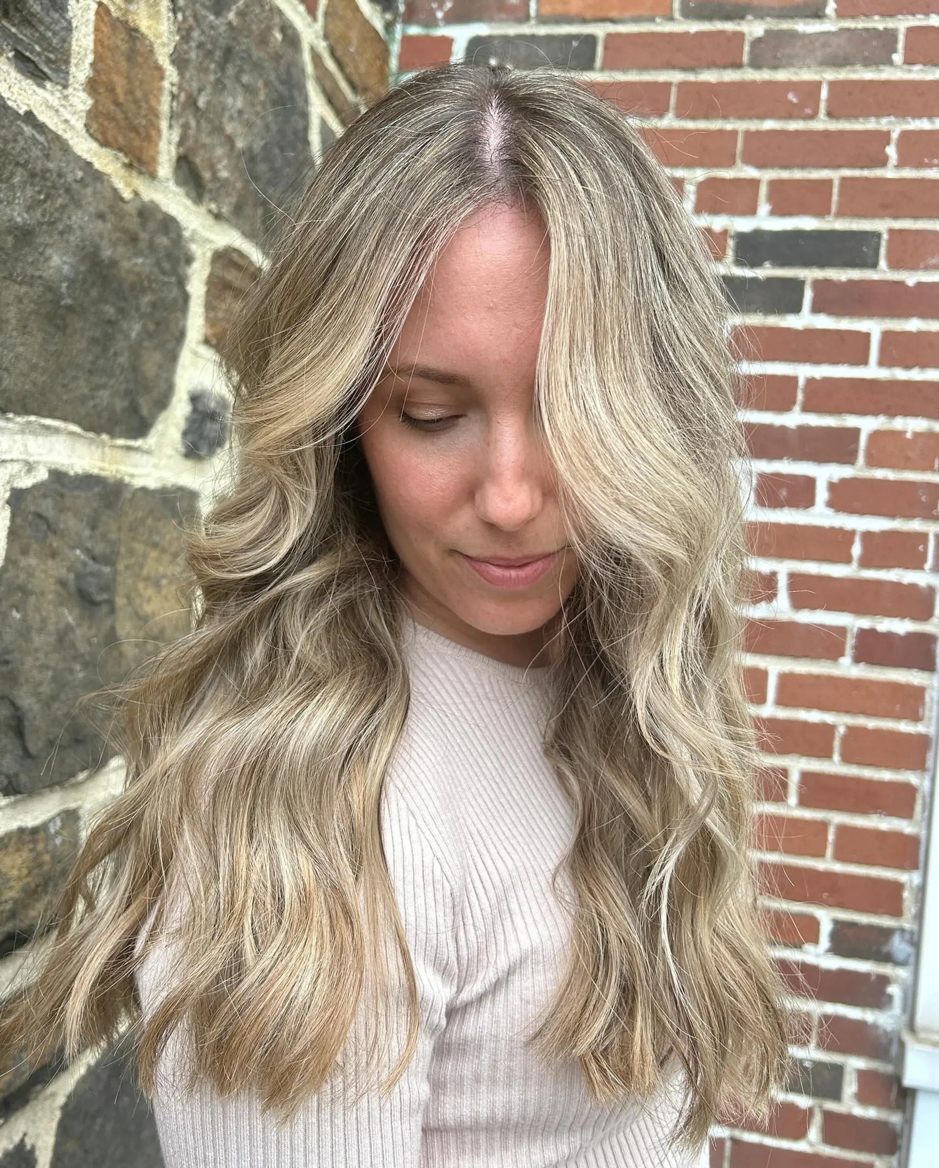 Long blonde hair featuring dimensional balayage highlights styled in voluminous, soft loose waves with face-framing layers. 1