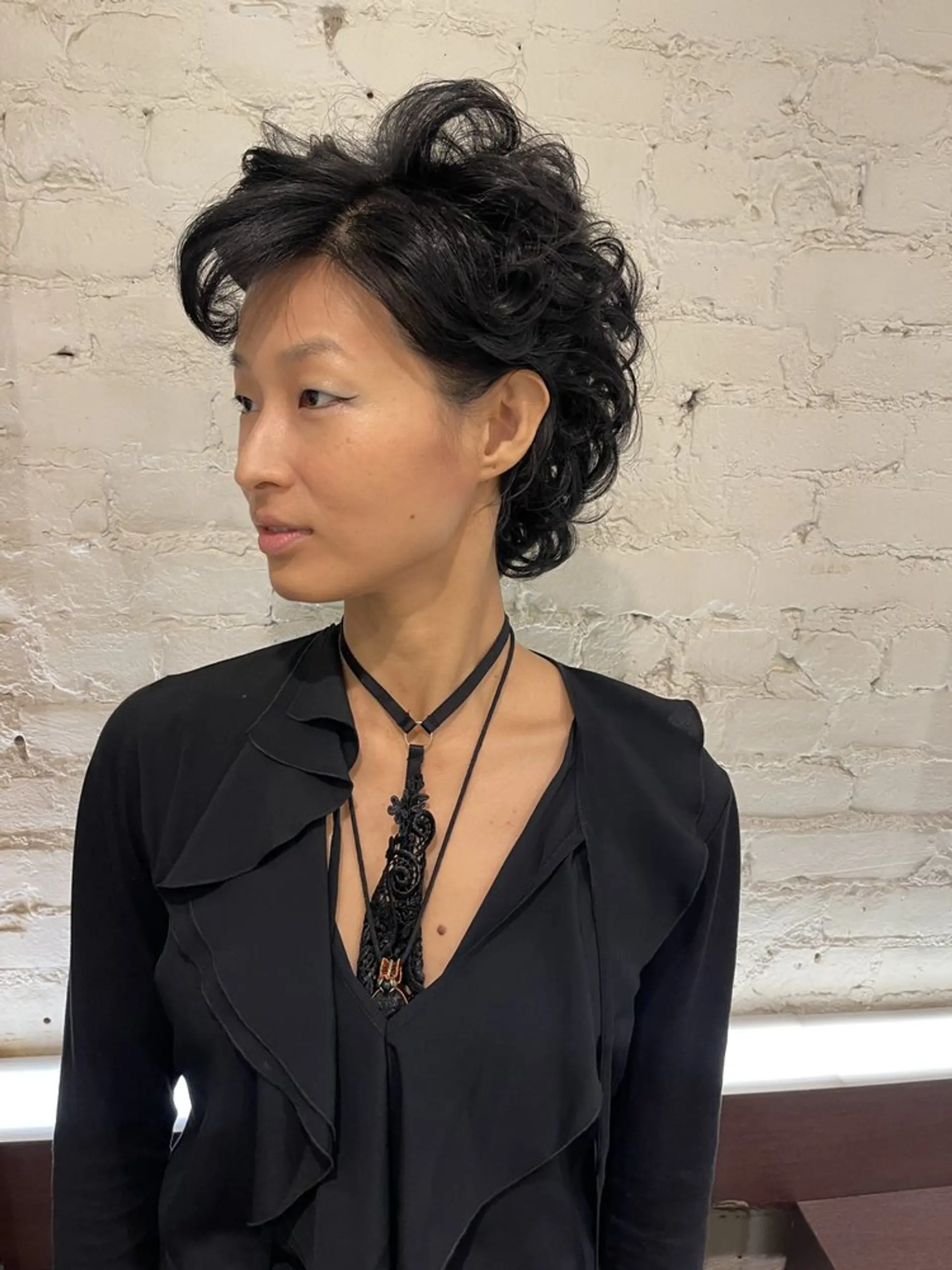 A short pixie cut styled with tight curls to give a modern and stylish look. 1