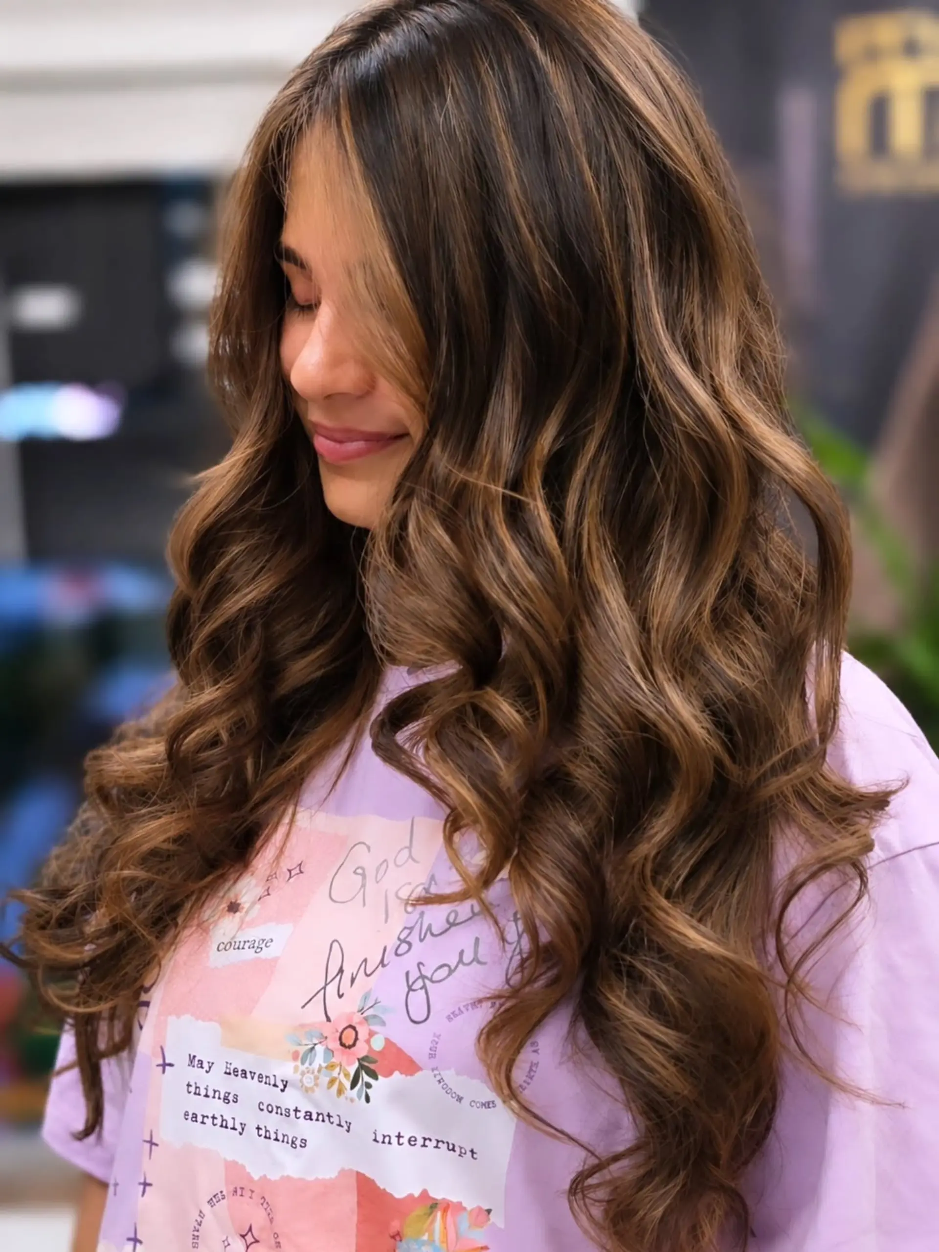 Long brown hair styled in voluminous loose waves with fine caramel balayage highlights. 1