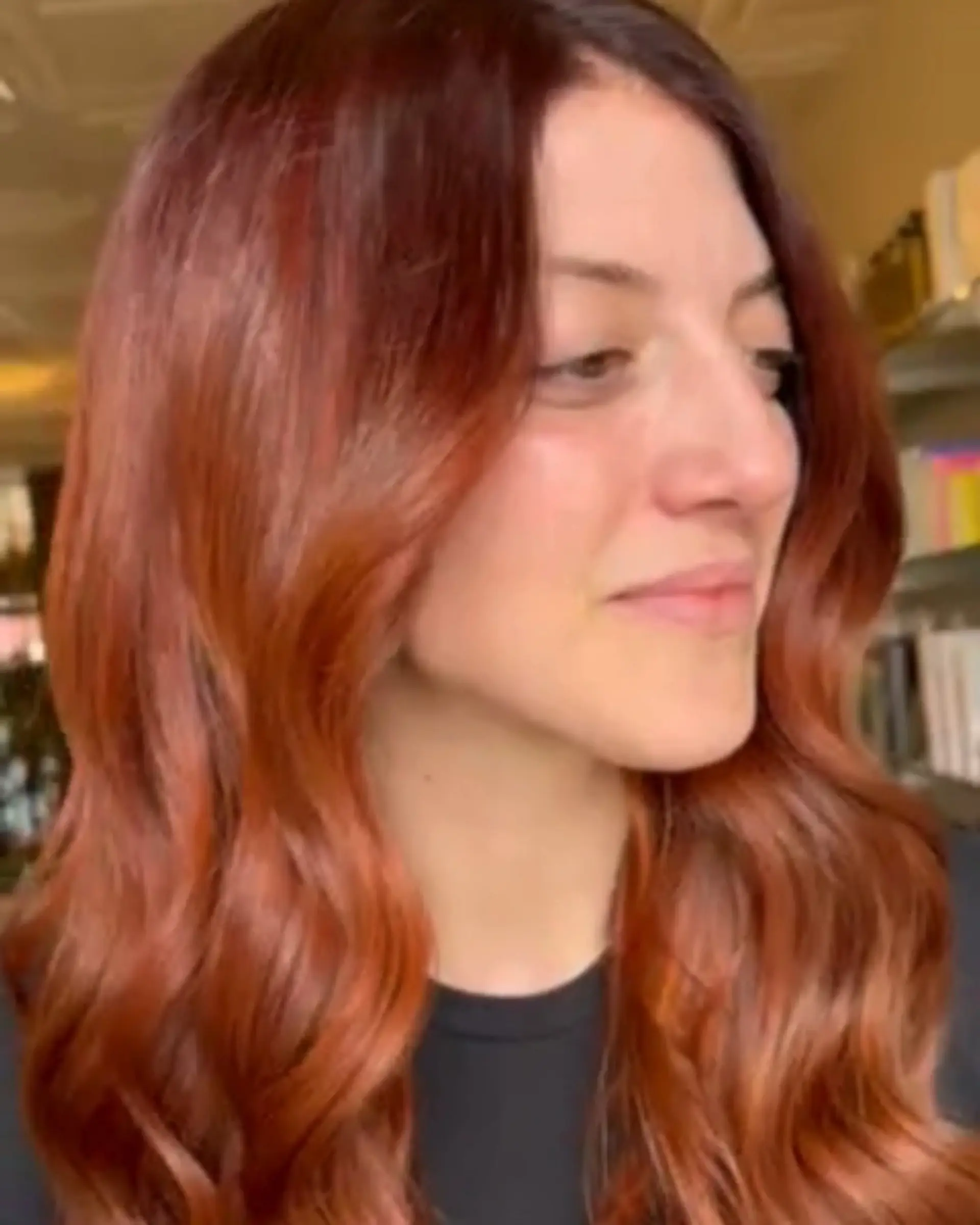 Rich copper balayage styled into glossy, loose waves with a center part. 1