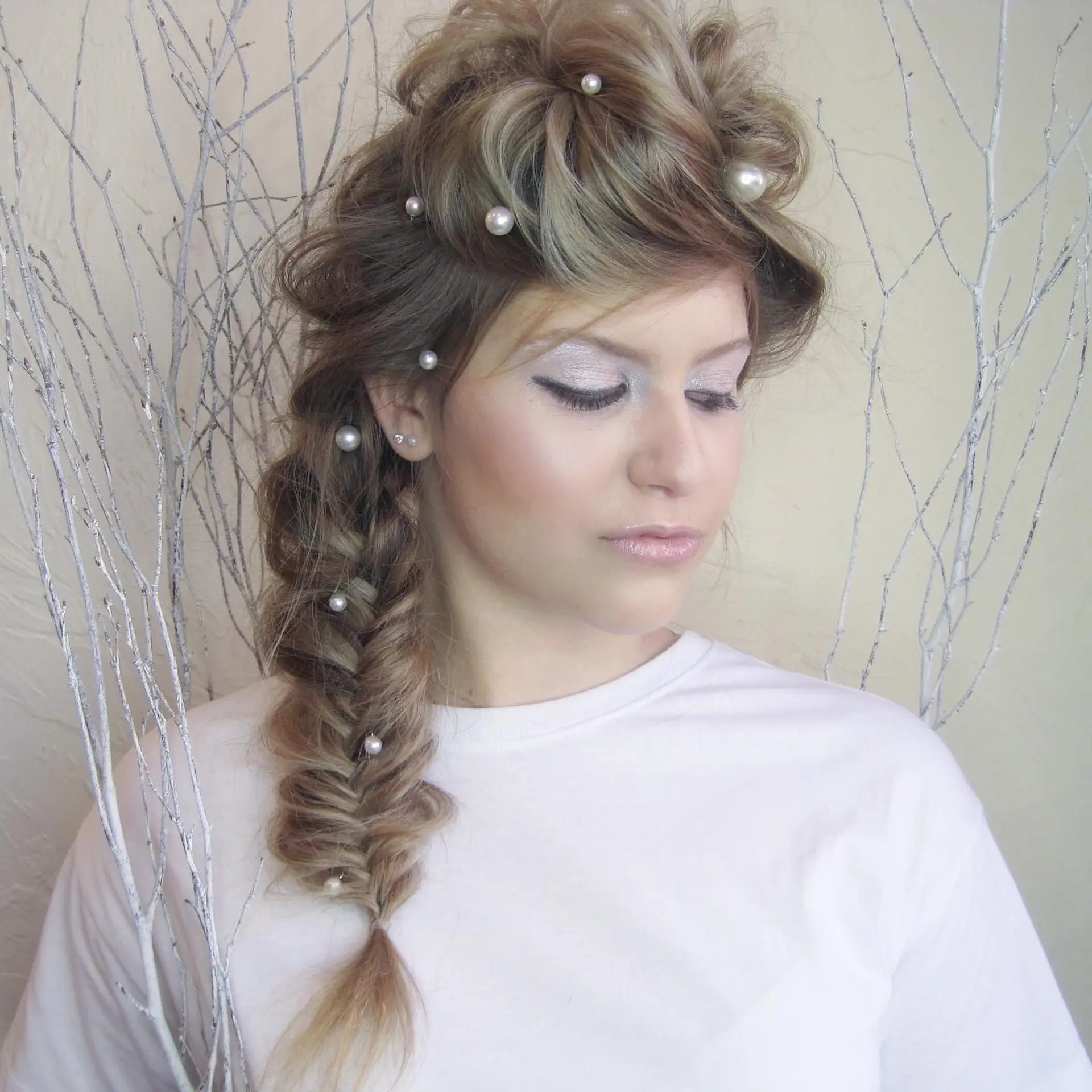 A textured side fishtail braid styled with a voluminous editorial crown and dotted with pearl embellishments. 1