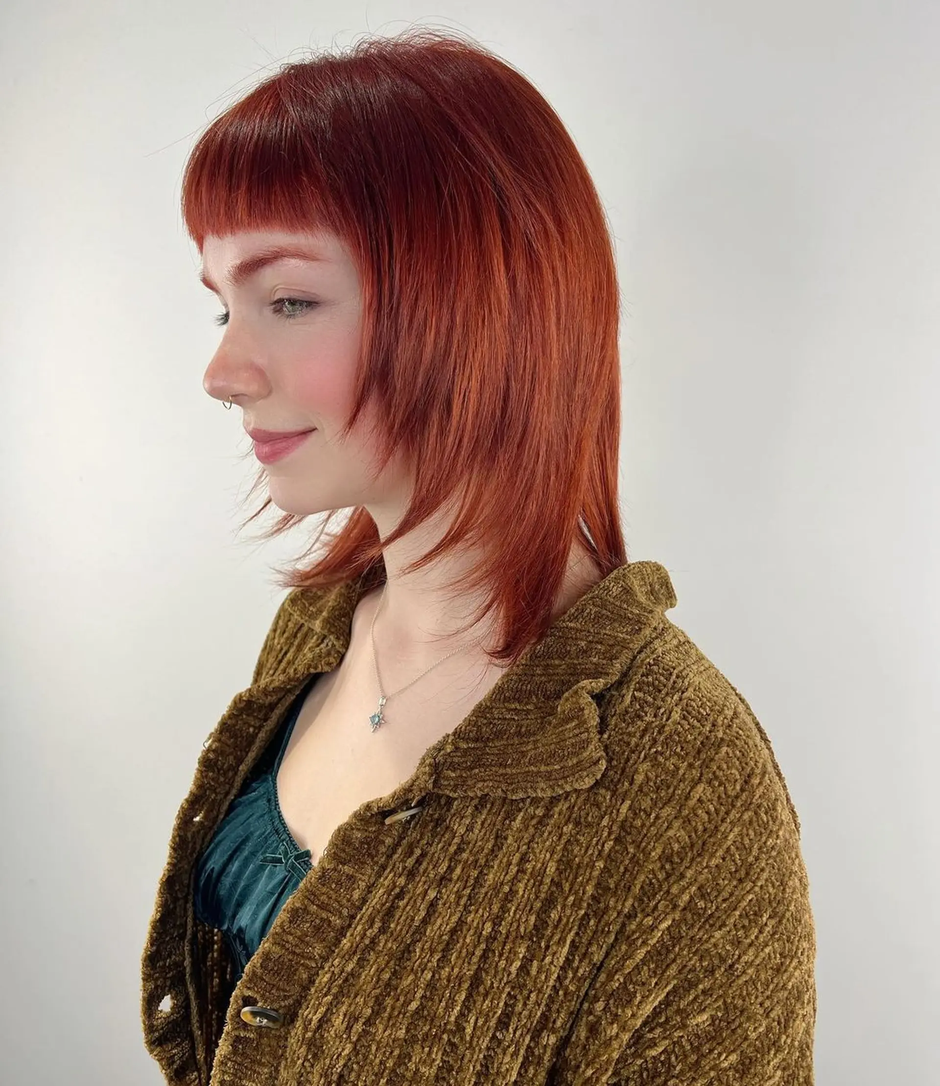 Straight, shoulder-length hair in a rich red hue, styled with blunt bangs and layered throughout for added texture and movement. 1