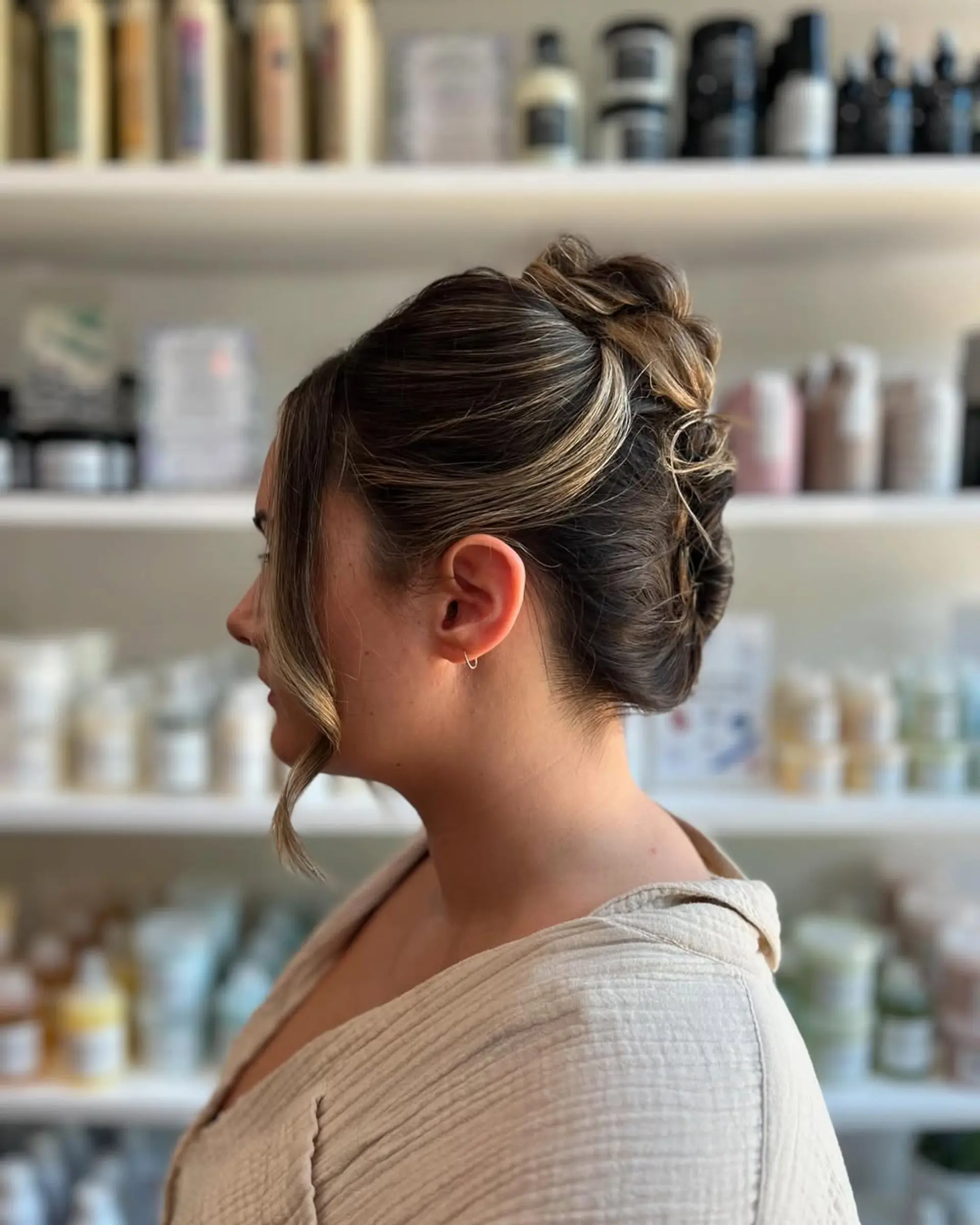 An elegant twisted updo with face-framing tendrils and dimensional caramel and blonde highlights, creating a sophisticated and soft look. 1