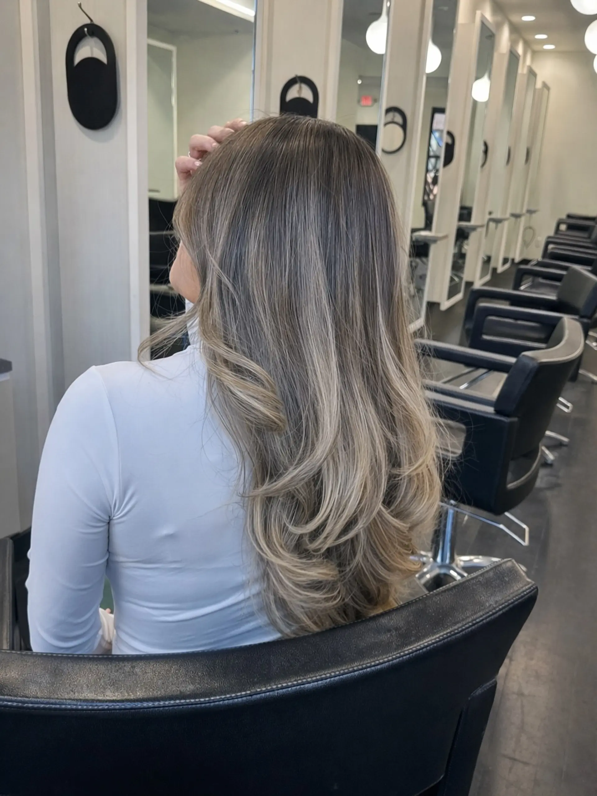 Long layered dimensional ash blonde balayage styled with a smooth blowout and softly curled ends. 1