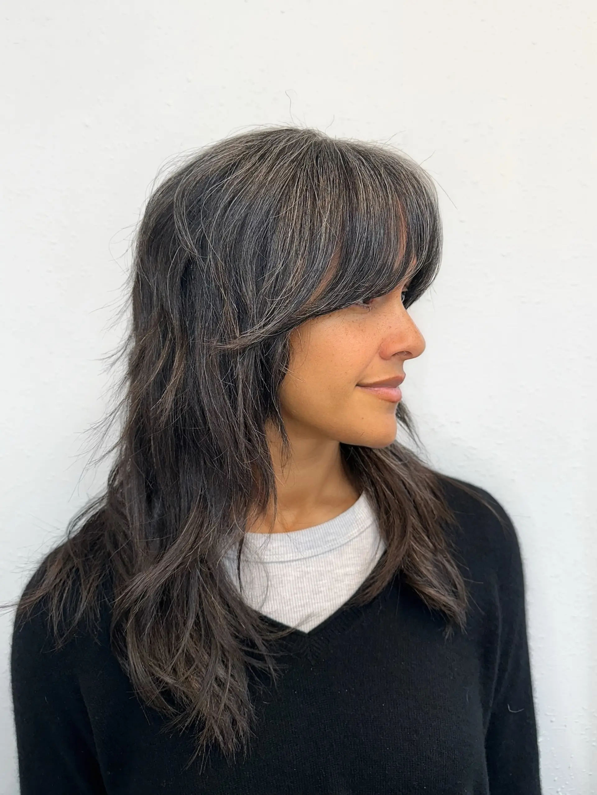 A modern, textured shag haircut featuring brow-skimming curtain bangs and soft, piecey layers for effortless volume. 1