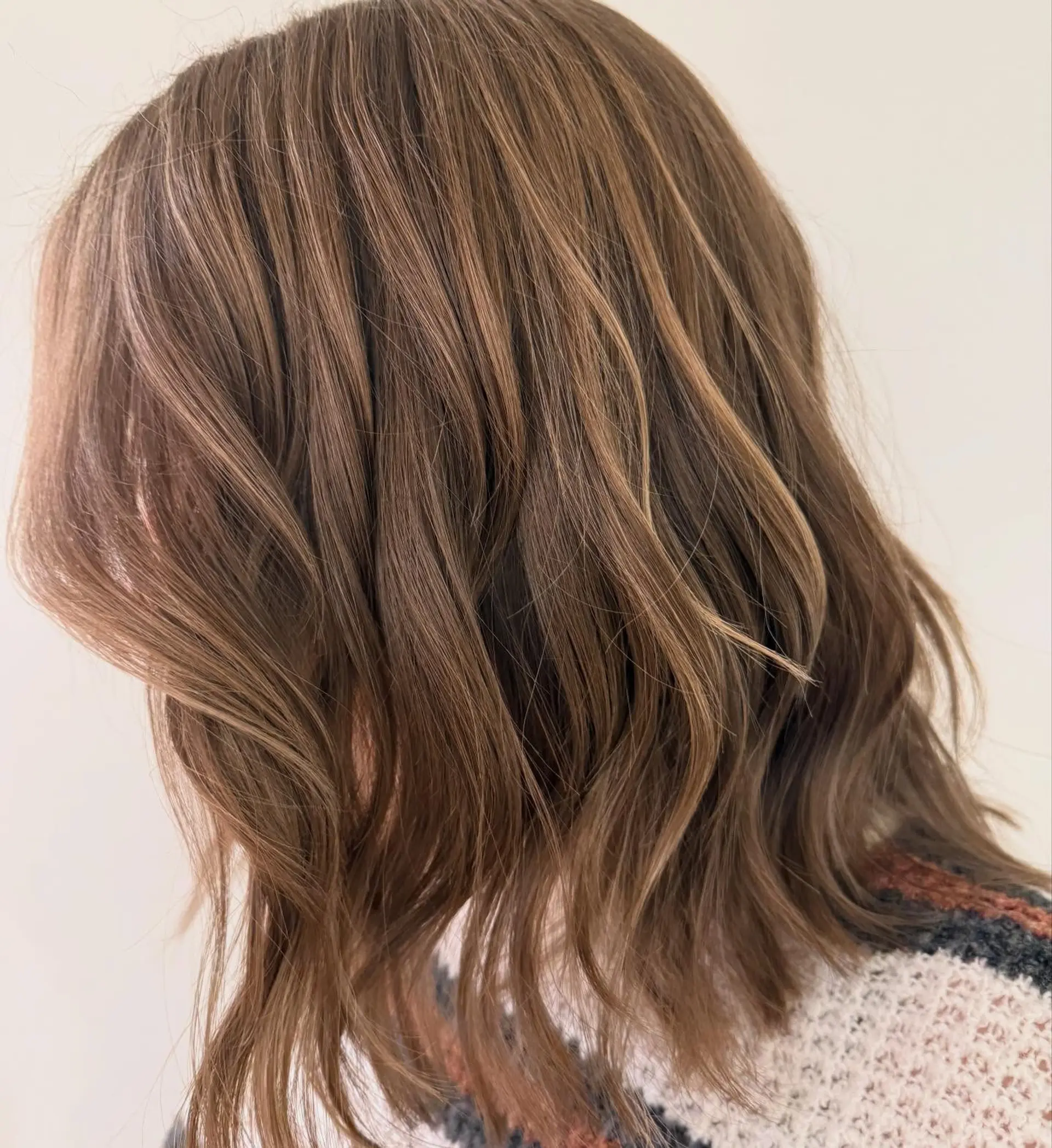 Shoulder-length textured bob styled in loose, lived-in waves with subtle dimensional highlights. 1
