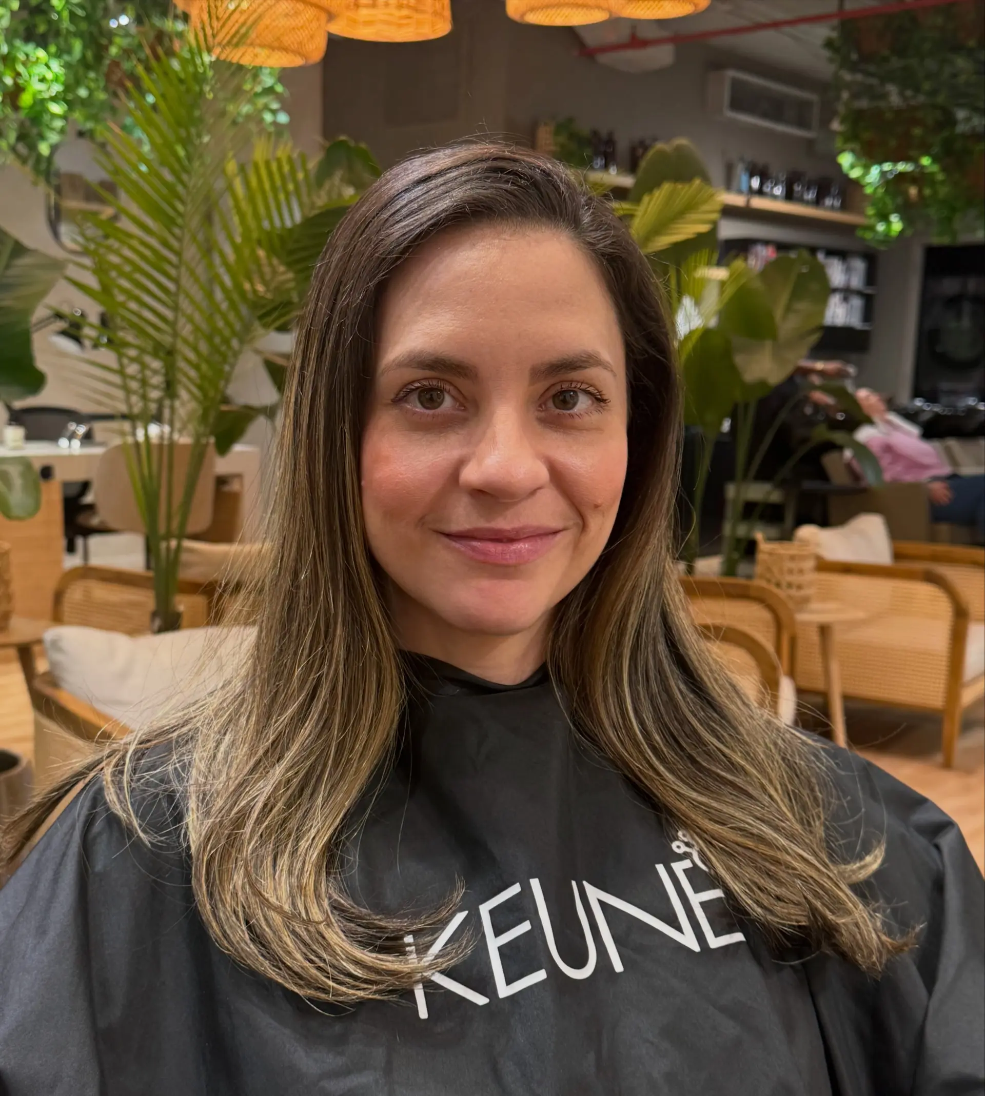 Long dimensional brunette hair with soft caramel highlights blended through the mid-lengths, styled into a smooth blowout with turned-in ends. 1
