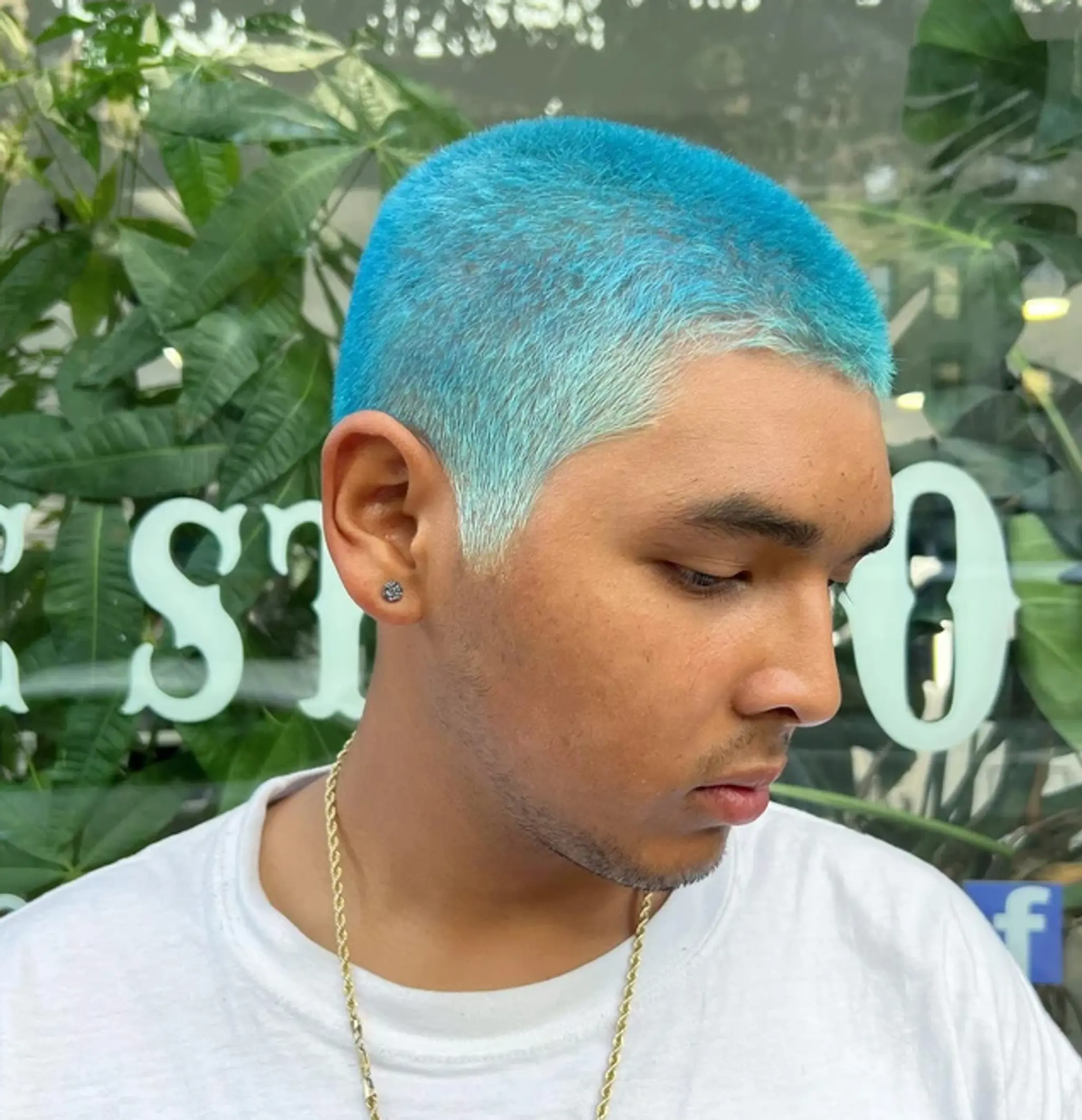 A very short, electric blue buzz cut, creating a vibrant and bold statement with neatly trimmed edges.