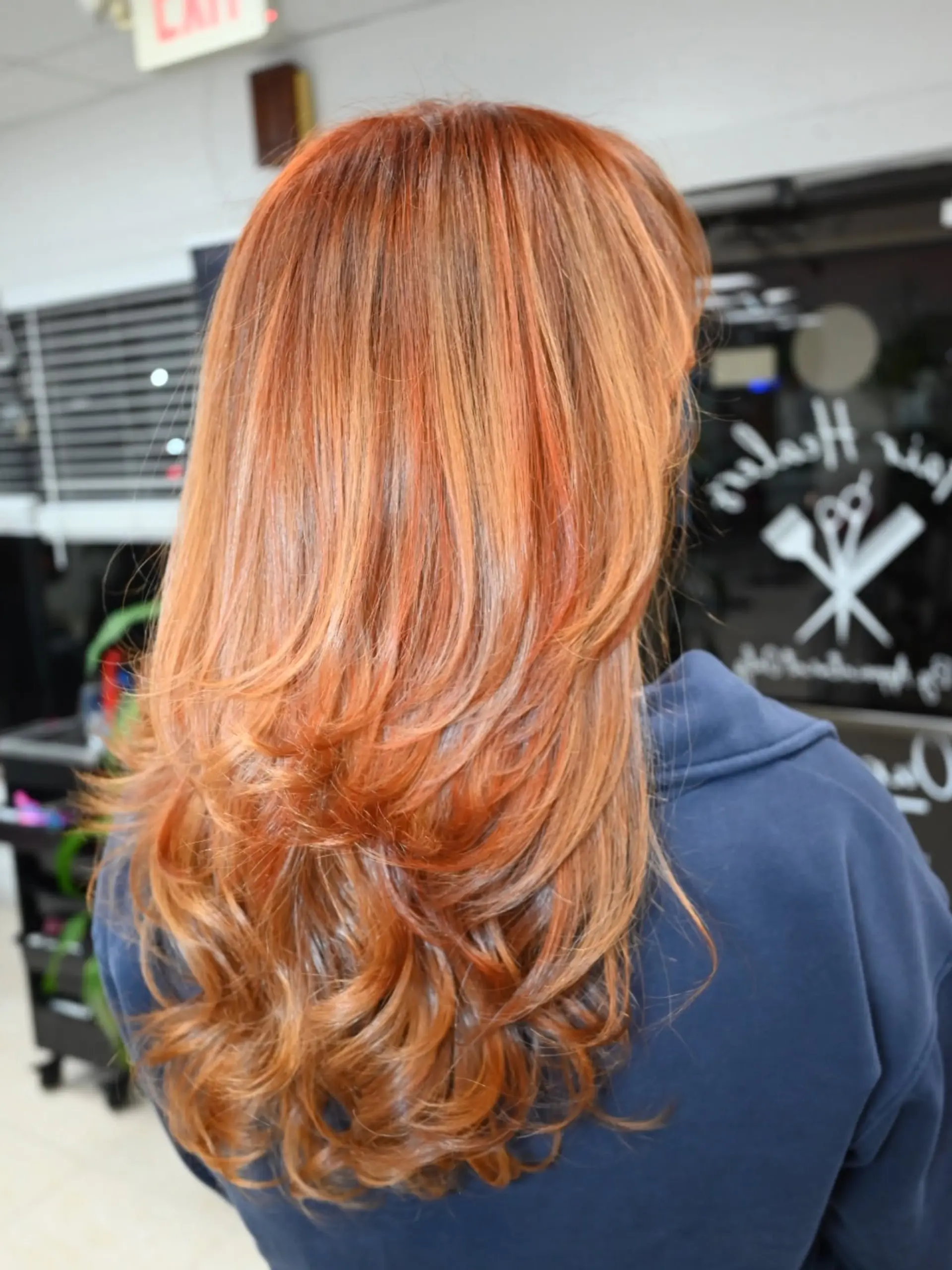 Long layered copper auburn hair styled with smooth face-framing layers and soft curls at the ends, enhanced with subtle lowlights. 1