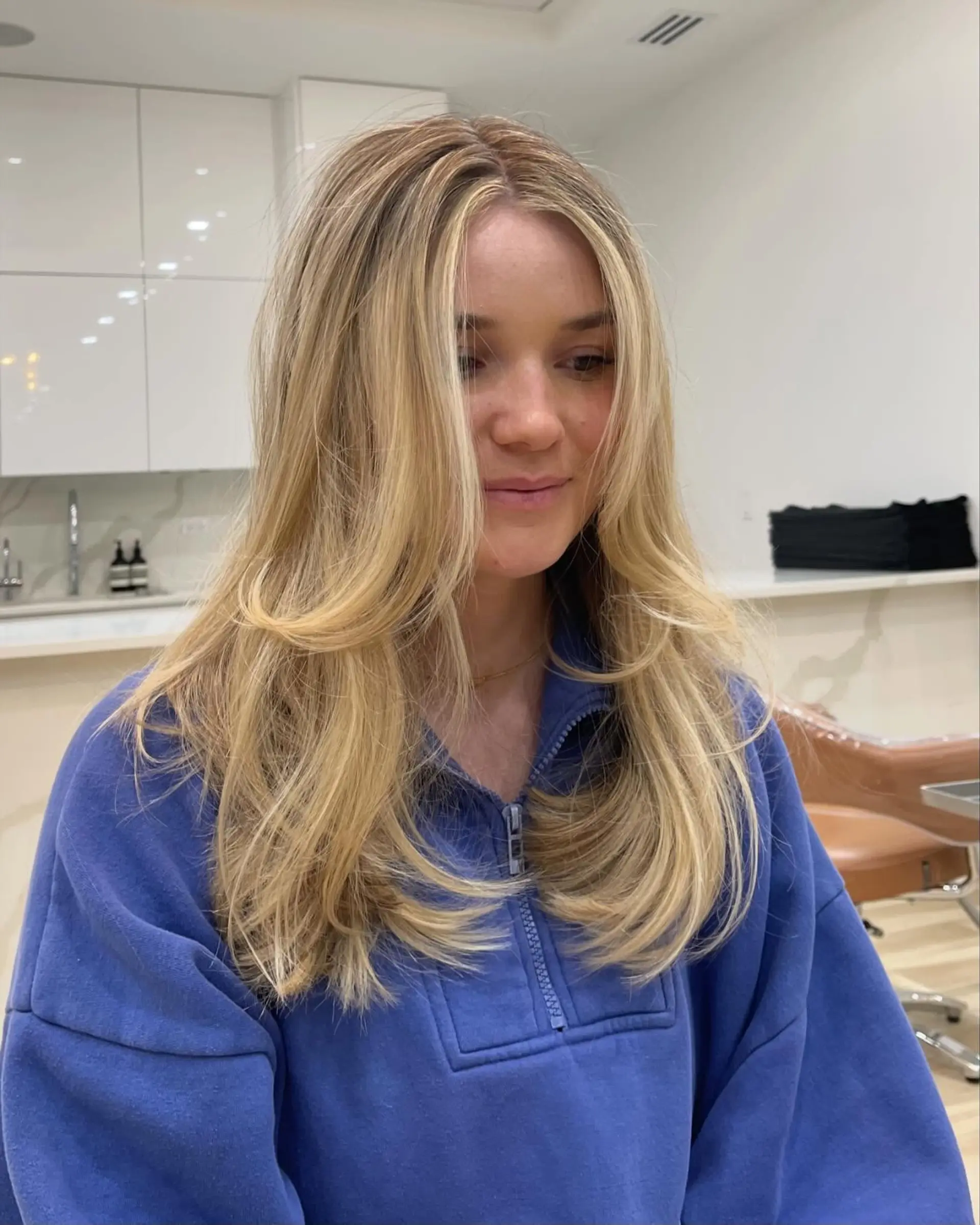 Long warm blonde hair featuring soft face-framing layers styled in a voluminous, rounded blowout. 1