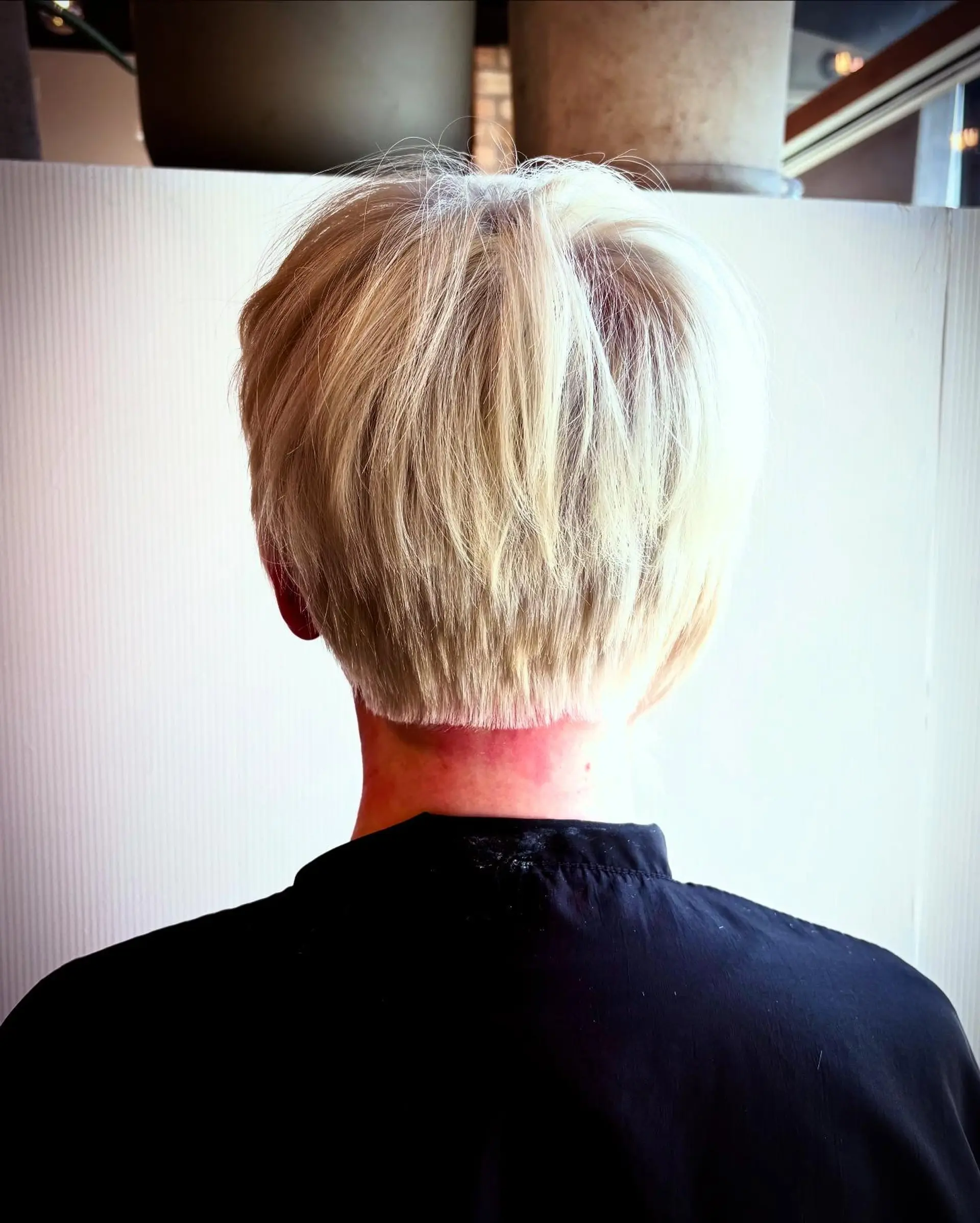 A blunt-nape platinum blonde pixie cut with soft, textured layers throughout the crown. 1