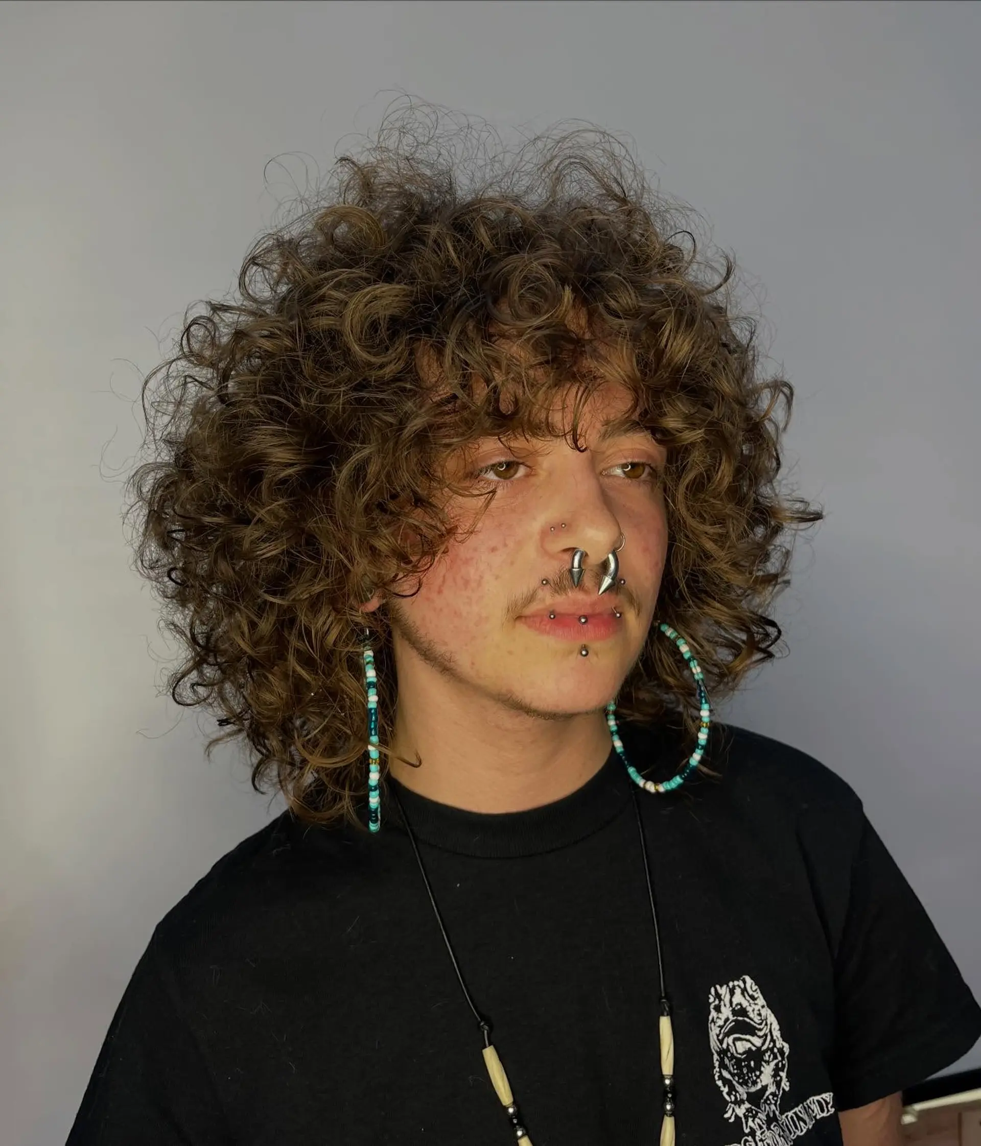 A voluminous curly shag haircut featuring textured layers and defined curly bangs framing the face. 1
