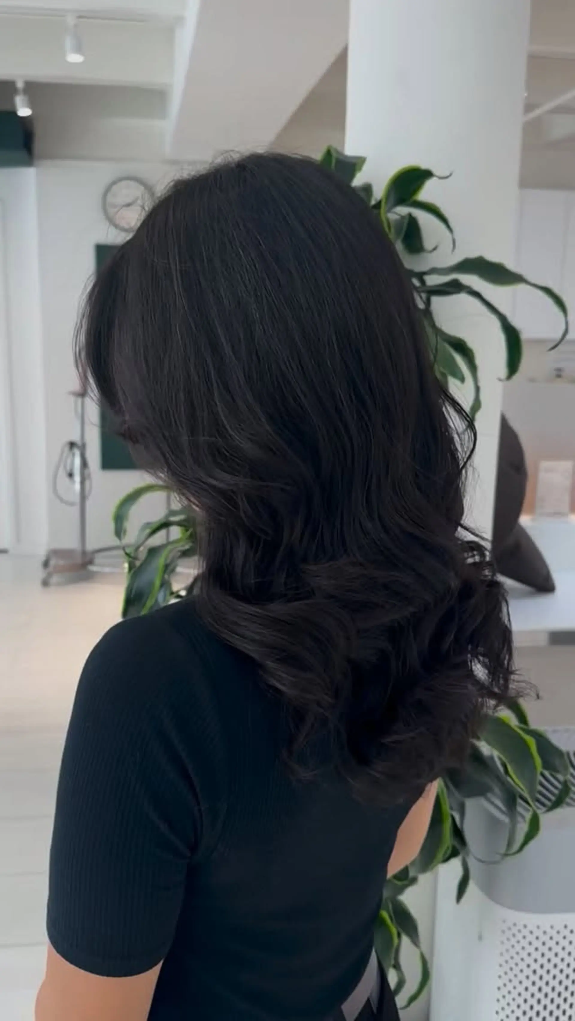 Long dark hair styled into voluminous, loose cascading waves with defined bouncy curls at the ends. 1