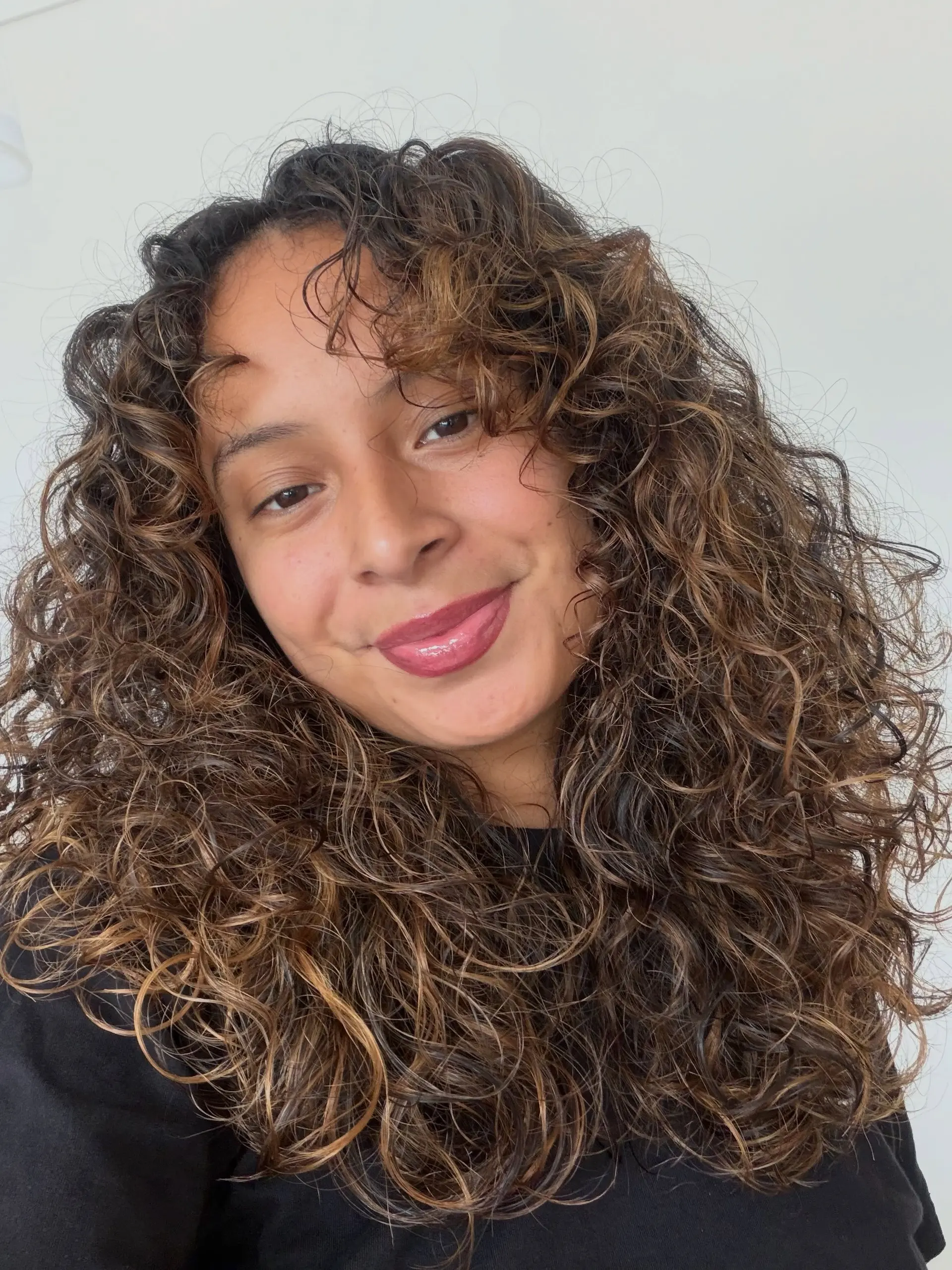 Naturally curly hair featuring honey and caramel balayage highlights for added dimension. 1