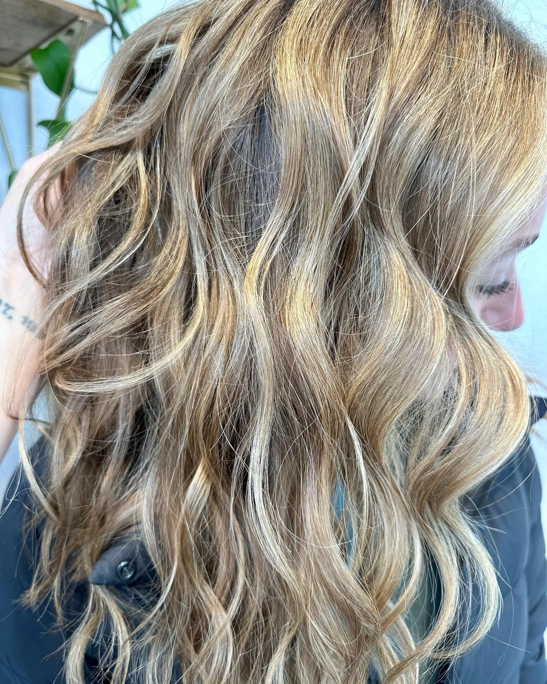 Medium-length loose wavy hair enhanced with multi-dimensional hand-painted honey and golden blonde balayage highlights. 1