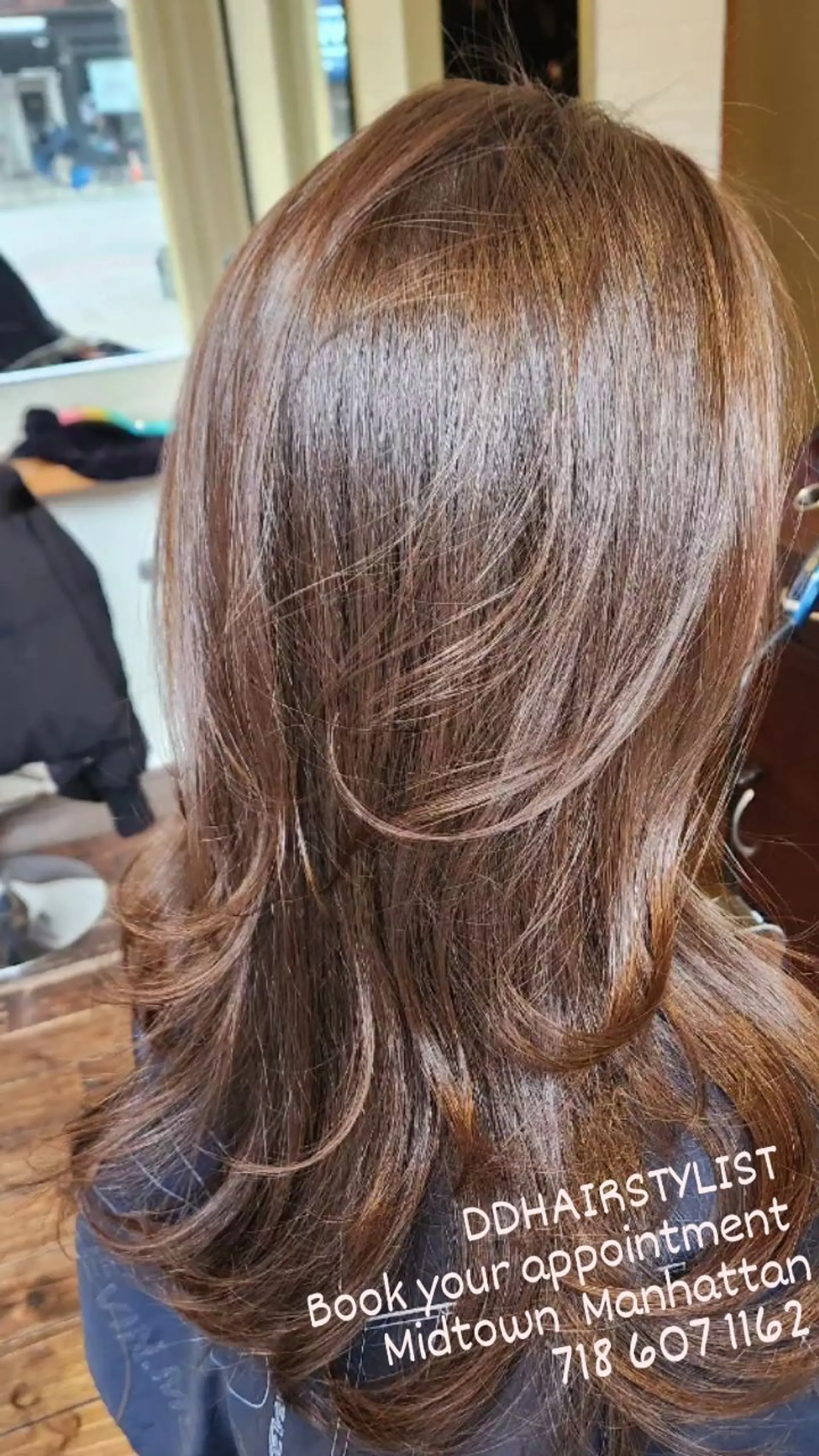Medium-to-long warm chestnut brown hair cut with soft, face-framing layers and styled into a voluminous blowout with flipped ends. 1