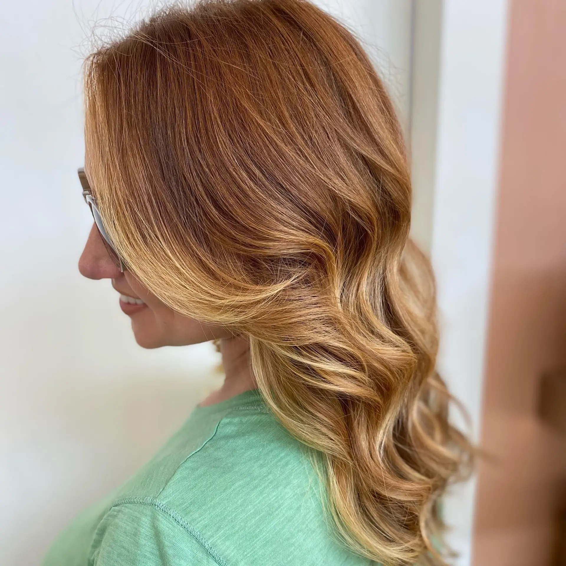 Warm copper-red hair softly transitioning into dimensional golden blonde tones, styled in loose, sweeping waves. 1