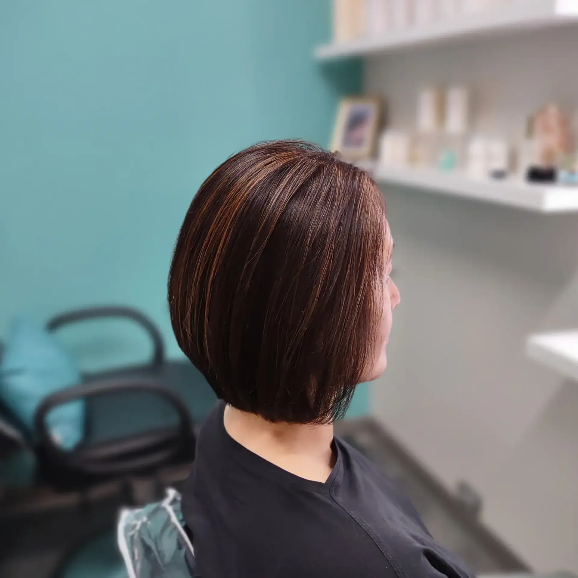 A sleek, rounded short bob styled straight with warm chestnut highlights woven throughout a dark brown base. 1