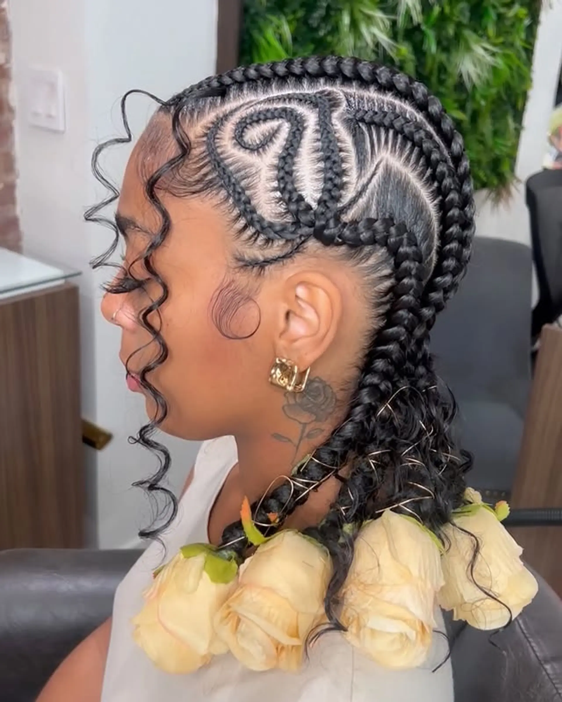 This hairstyle features intricate cornrow designs that transition into long braids, embellished with flower accents for a unique and stylish look. 1