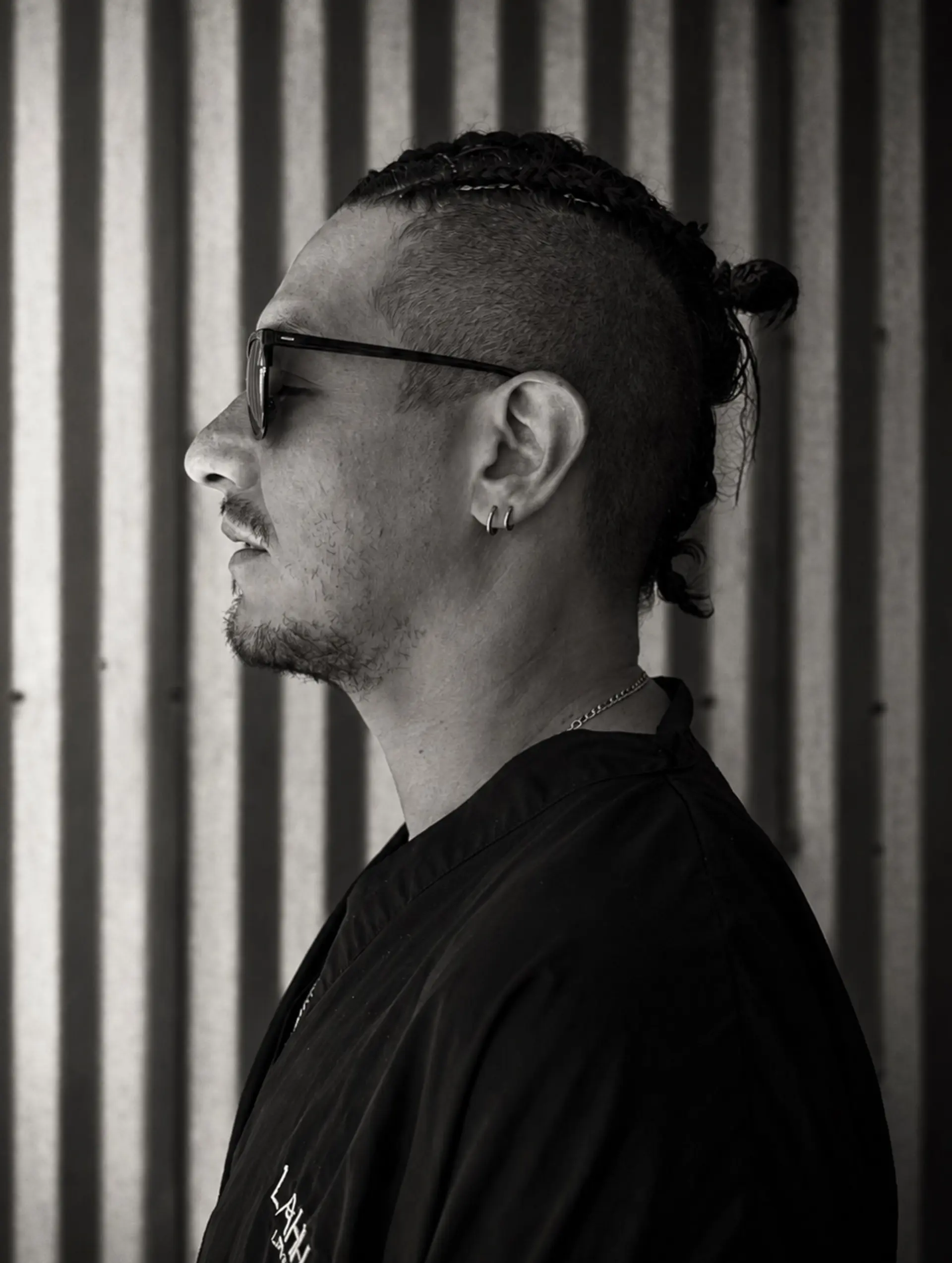 A men's undercut featuring tight braided rows on the crown gathered into a top knot, paired with closely shaved sides. Estimate scope: Haircut component only, from $85. Cornrow braiding/top-knot styling is not priced by the selected Gentleman's Cut mapping. Do not label $85 as the complete braided-look total; braiding and finishing scope/price remain unknown. 1
