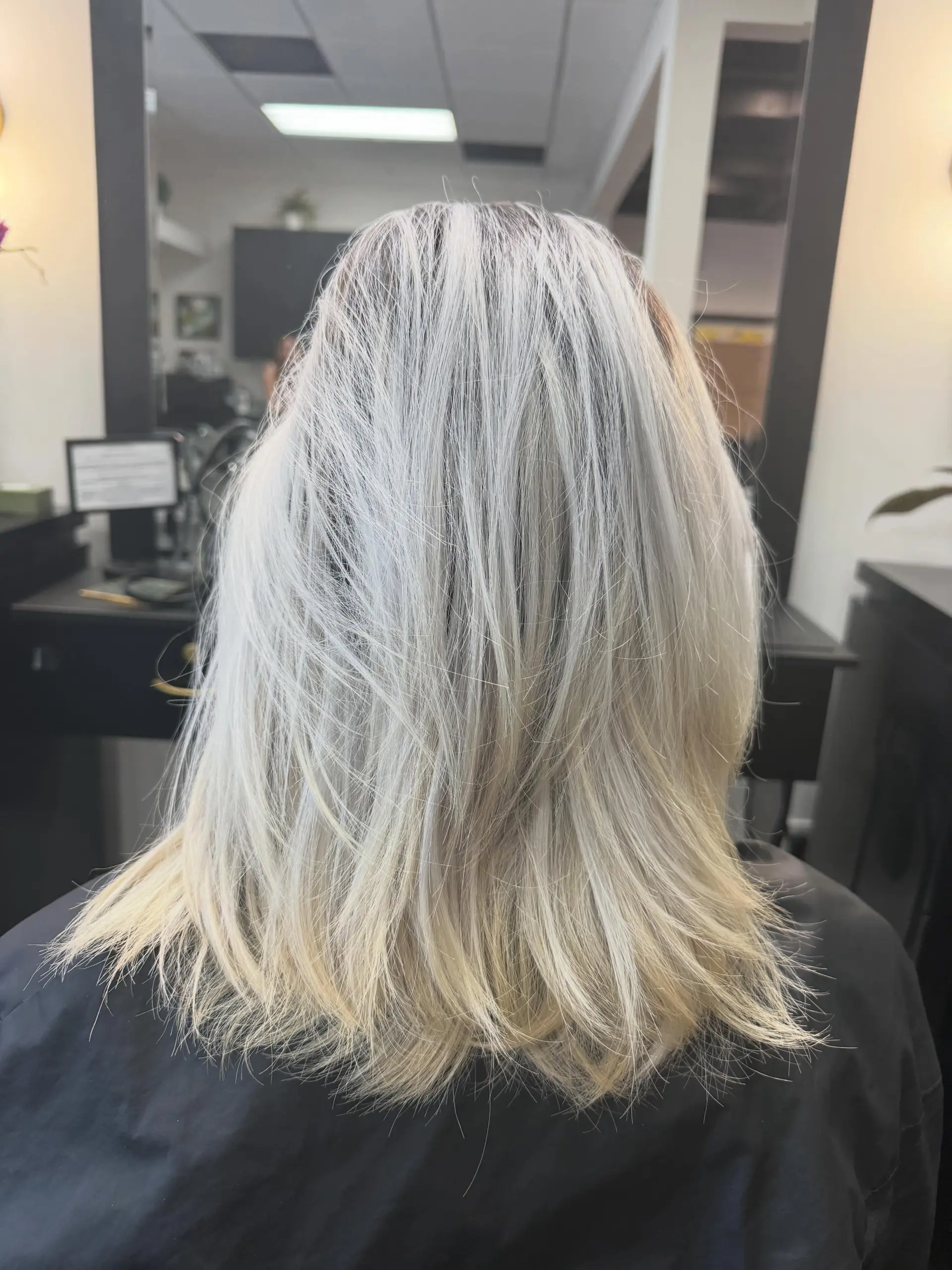 A cool platinum blonde shoulder-length cut featuring shattered layers and light, piecey texture throughout. 1