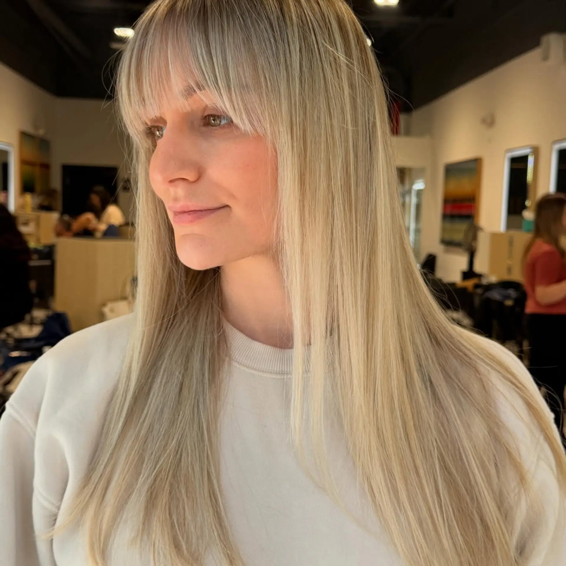 Sleek and straight bright blonde long hair paired with wispy, eyelash-grazing bangs. 1
