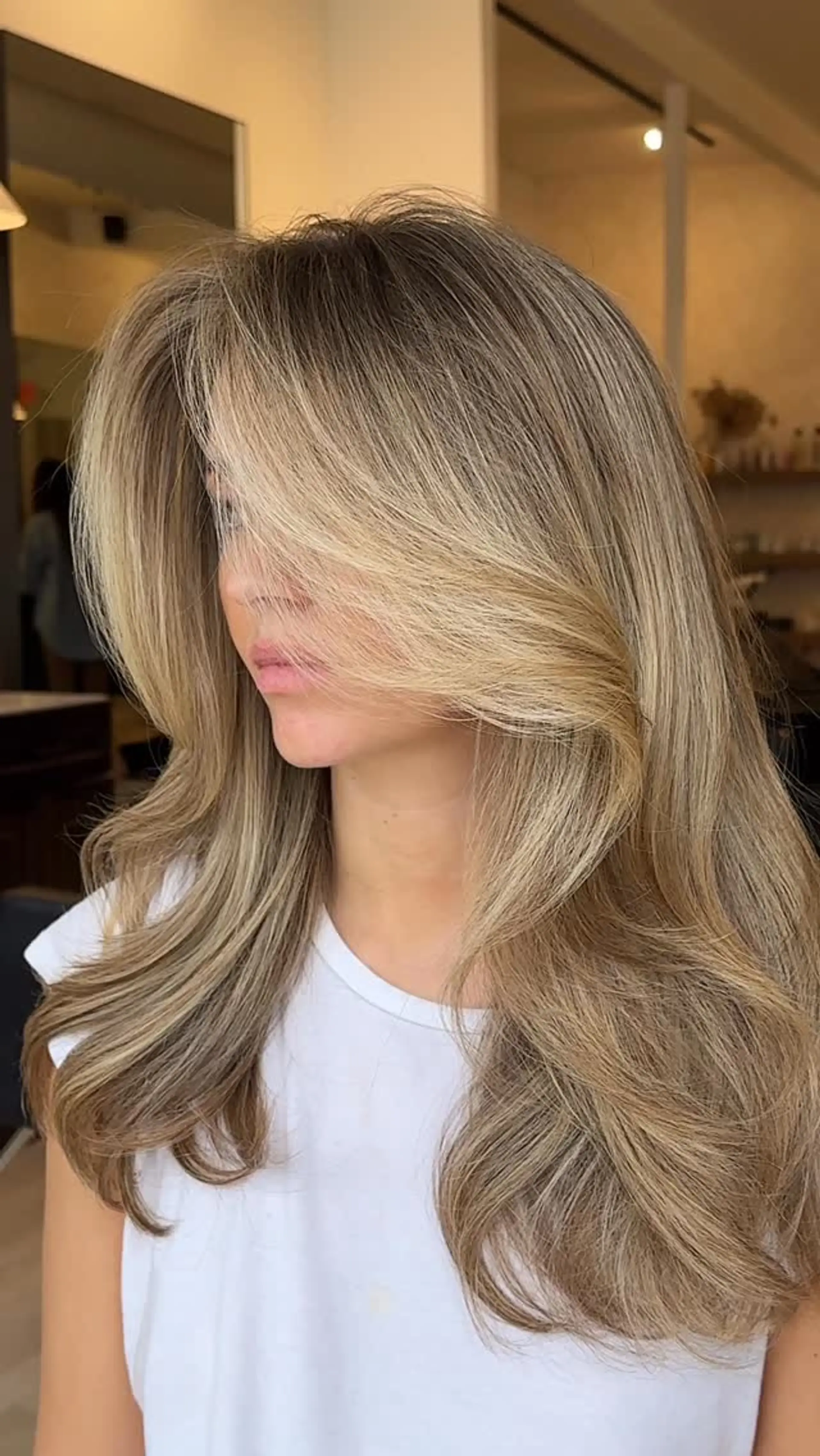 Long dimensional honey blonde hair styled in a voluminous blowout with sweeping face-framing layers. 1