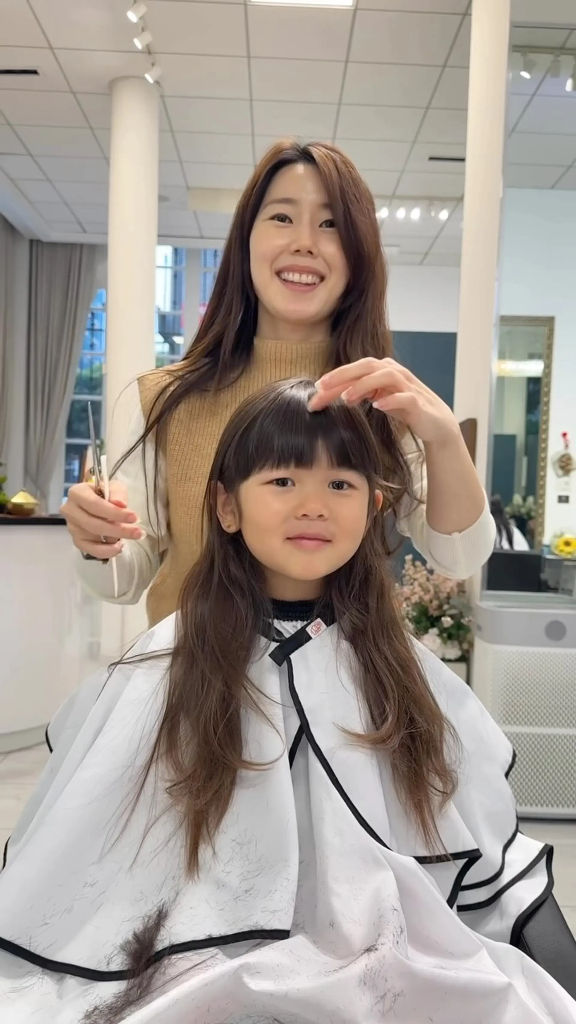 A young girl's long hairstyle featuring neatly cut straight blunt bangs and natural long layers. 1