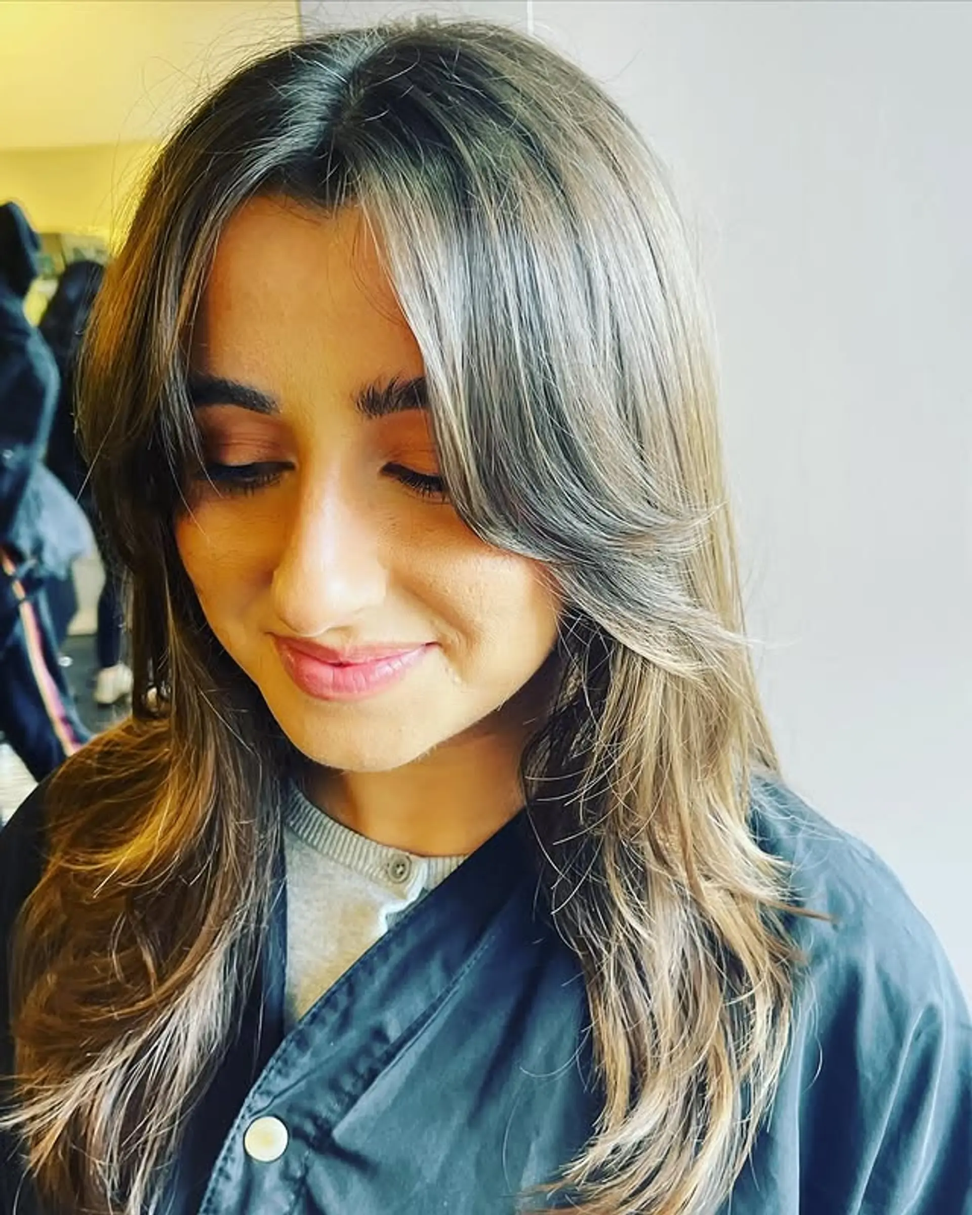 A medium-length layered hairstyle with face-framing curtain bangs. 1