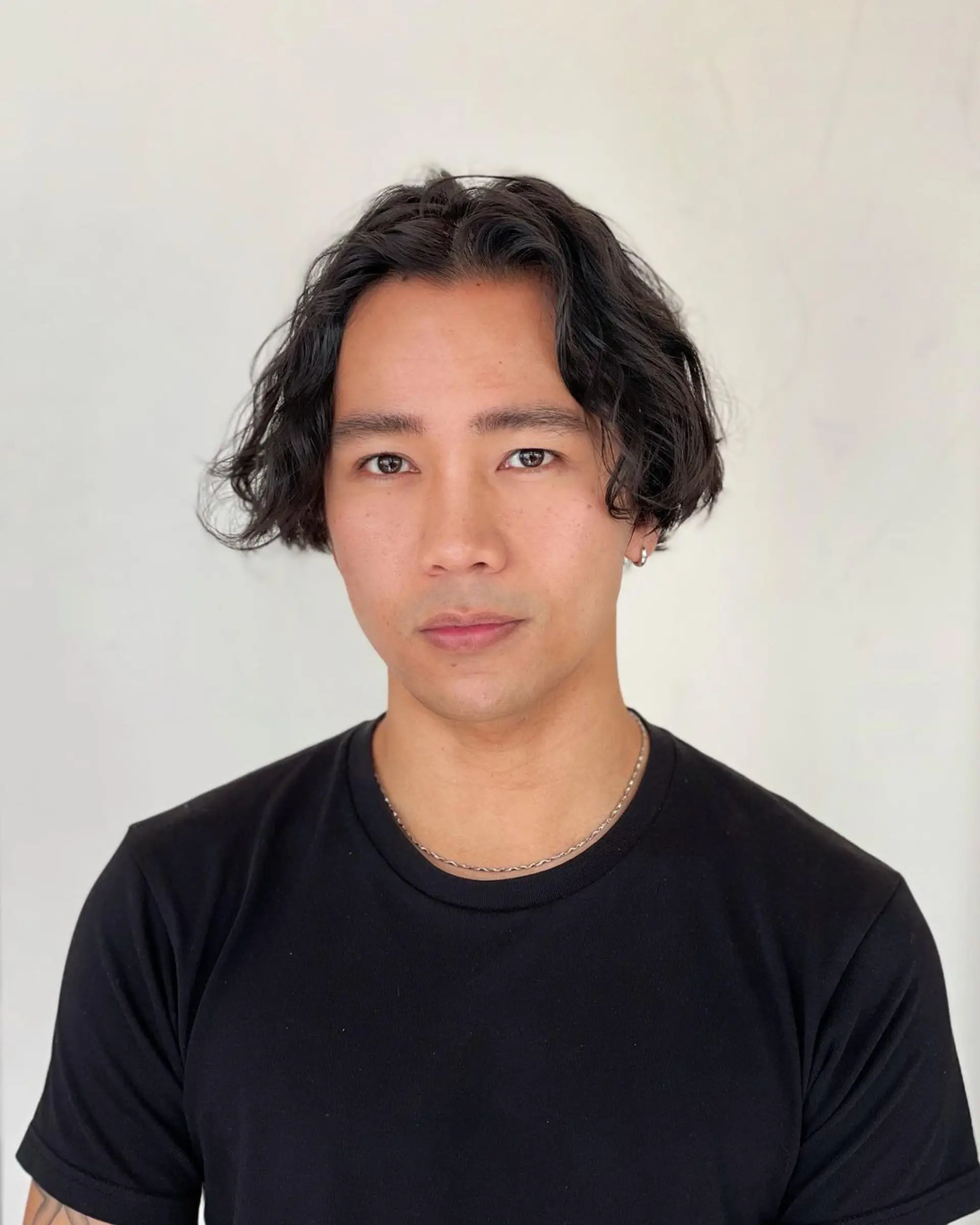 Medium length wavy hairstyle with a center part and ear-length waves, offering a casual and effortless appearance. 1