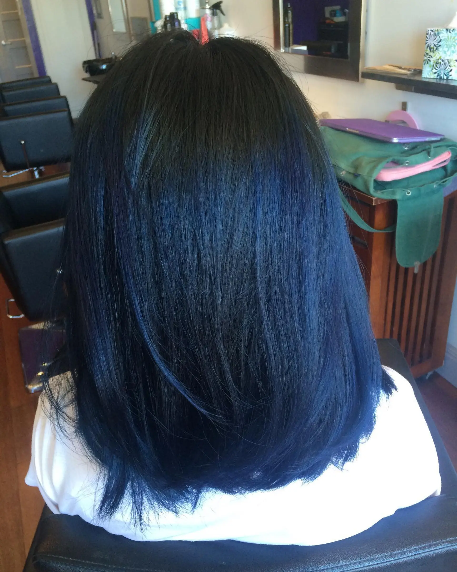 A medium-length straight cut featuring a rich, reflective midnight blue balayage over deep dark roots. 1