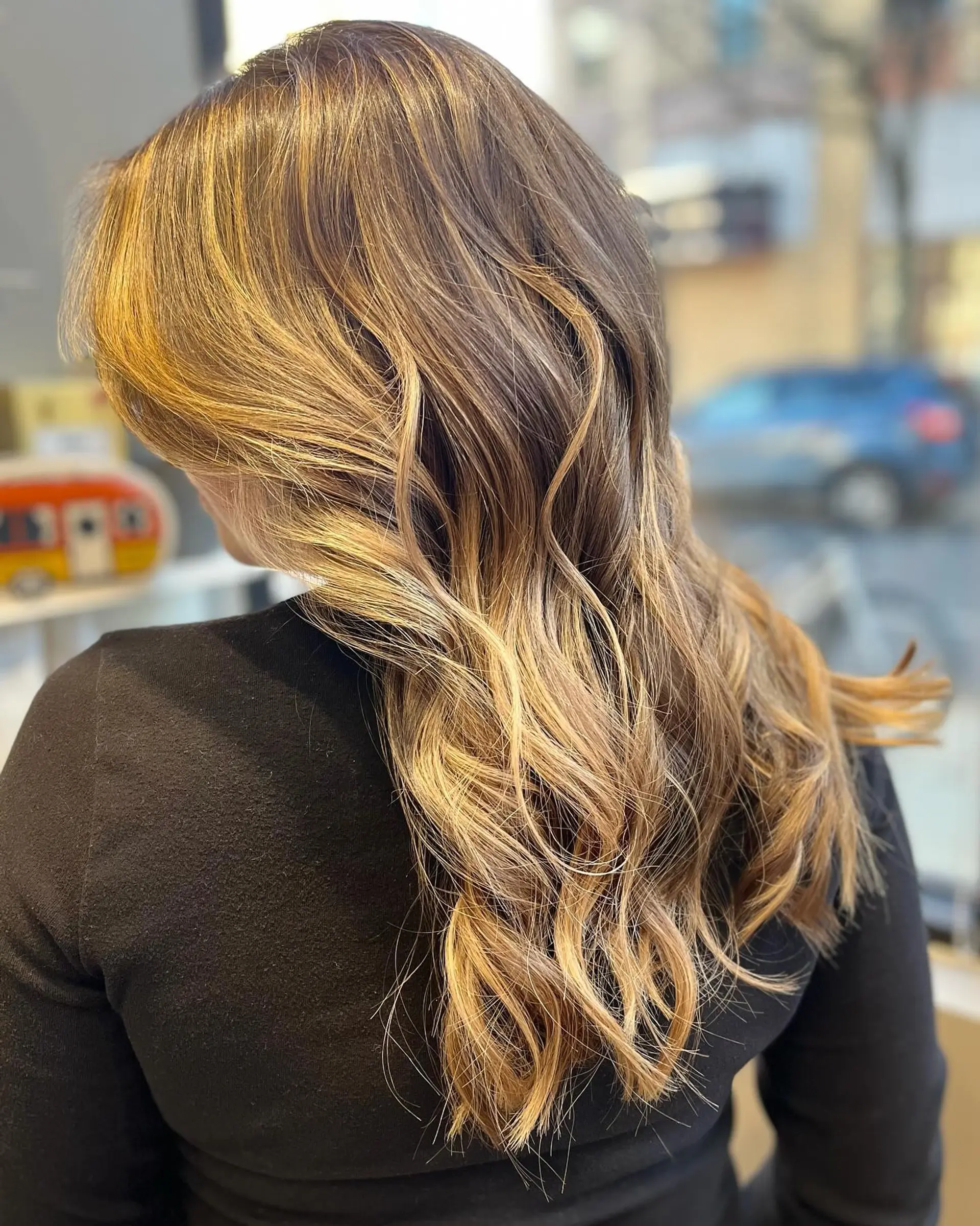 A long, wavy hairstyle with a seamless golden blonde balayage. 1