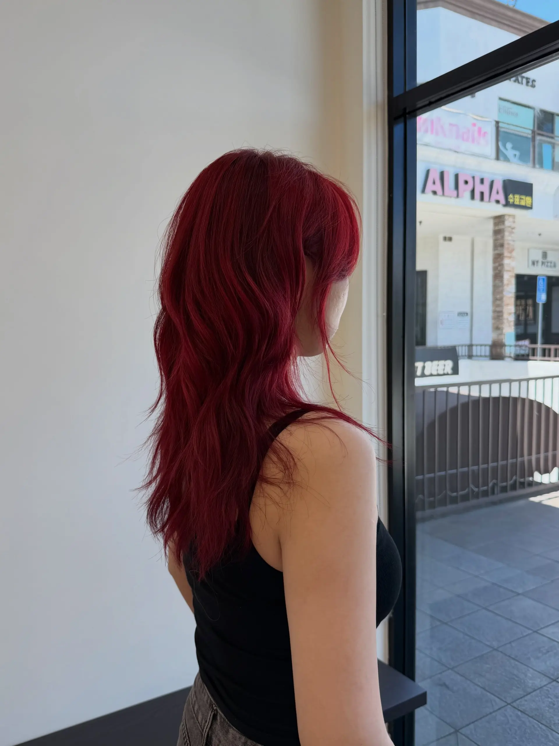 A vibrant crimson red long haircut featuring high layers and soft, effortless waves. 1