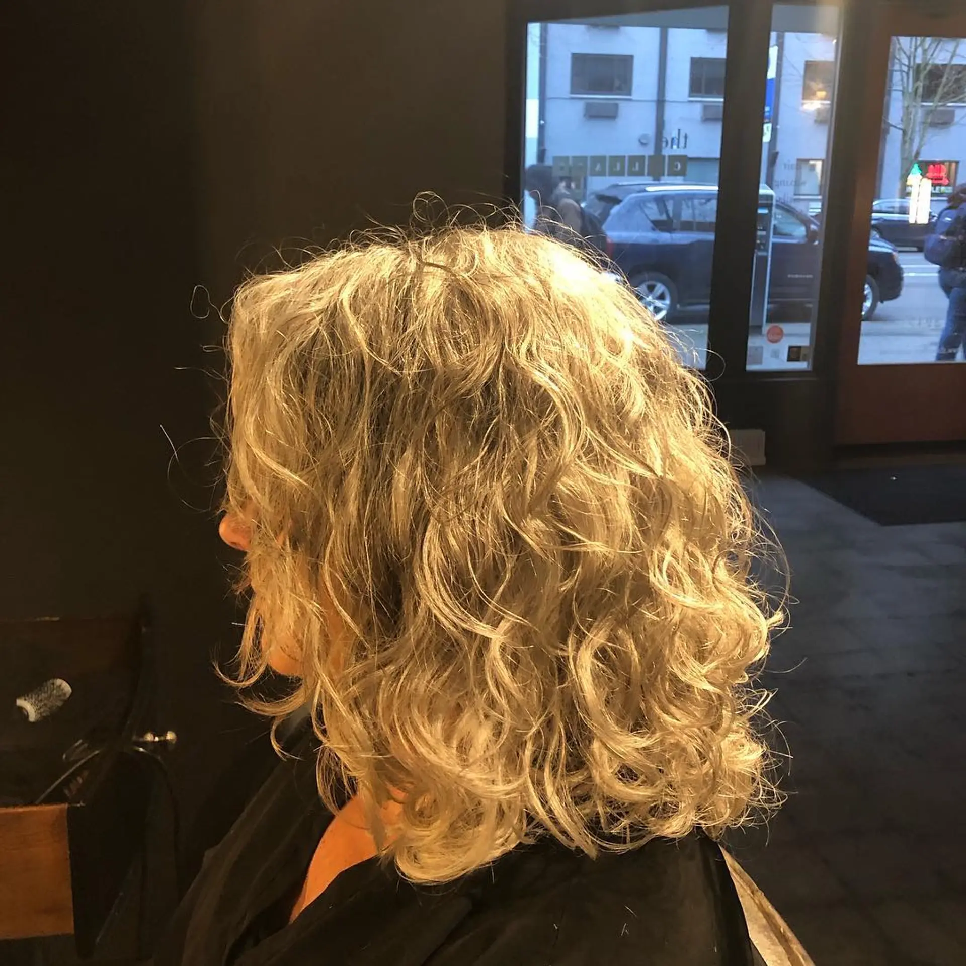 Medium-length curly cut styled with enhanced natural texture and defined ringlets. 1