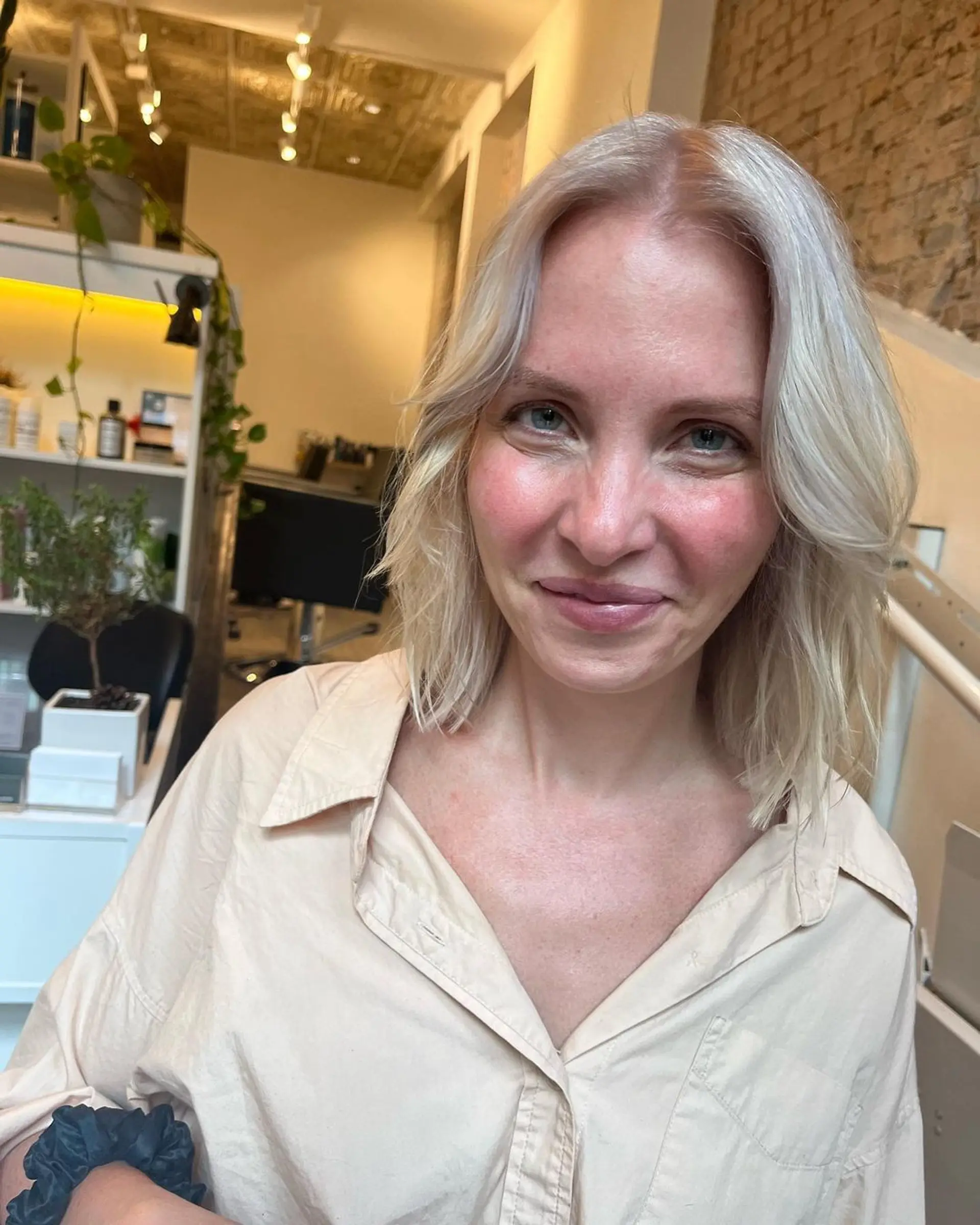 Medium-length platinum blonde hair with a wavy texture, side part, soft layers, and face-framing pieces. 1