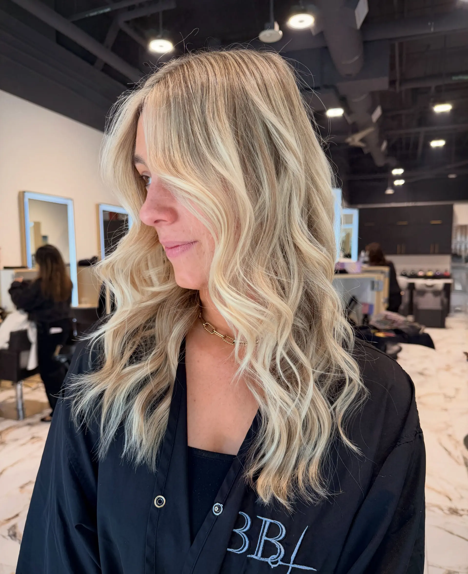 Long bright blonde hair styled in soft, loose waves with face-framing layers. 1