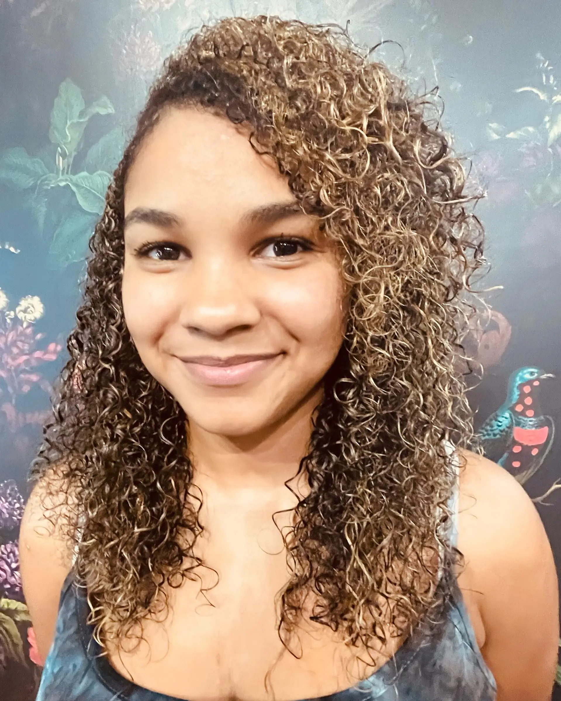 Medium-length defined curls styled with a side part and dimensional golden blonde highlights. 1