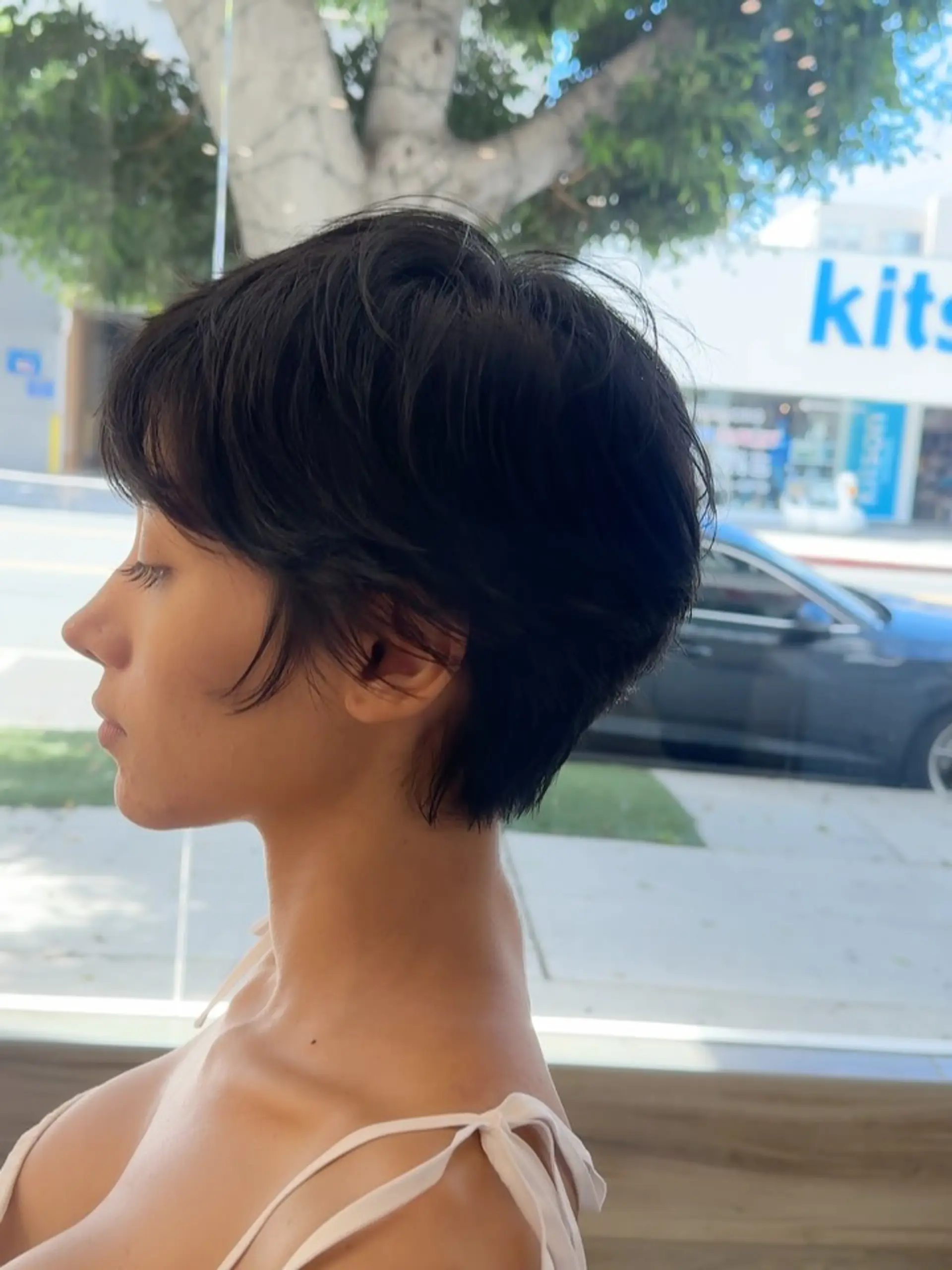 A soft, textured pixie cut featuring feathered layers, wispy sideburn pieces framing the ear, and gentle nape tapering. 1