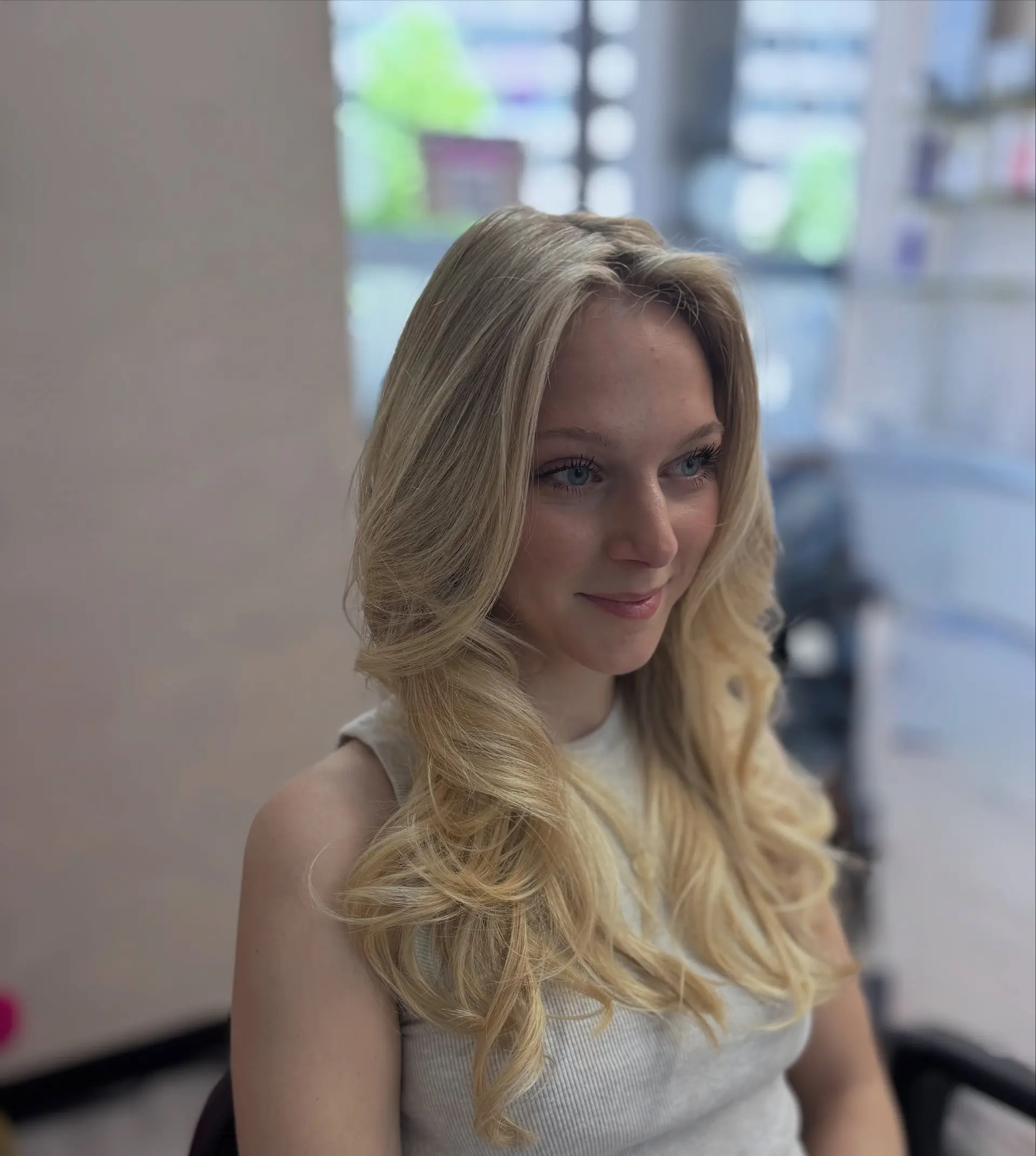 Long, bright blonde hair styled with a bouncy blowout featuring layered face-framing pieces and soft waves at the ends. 1