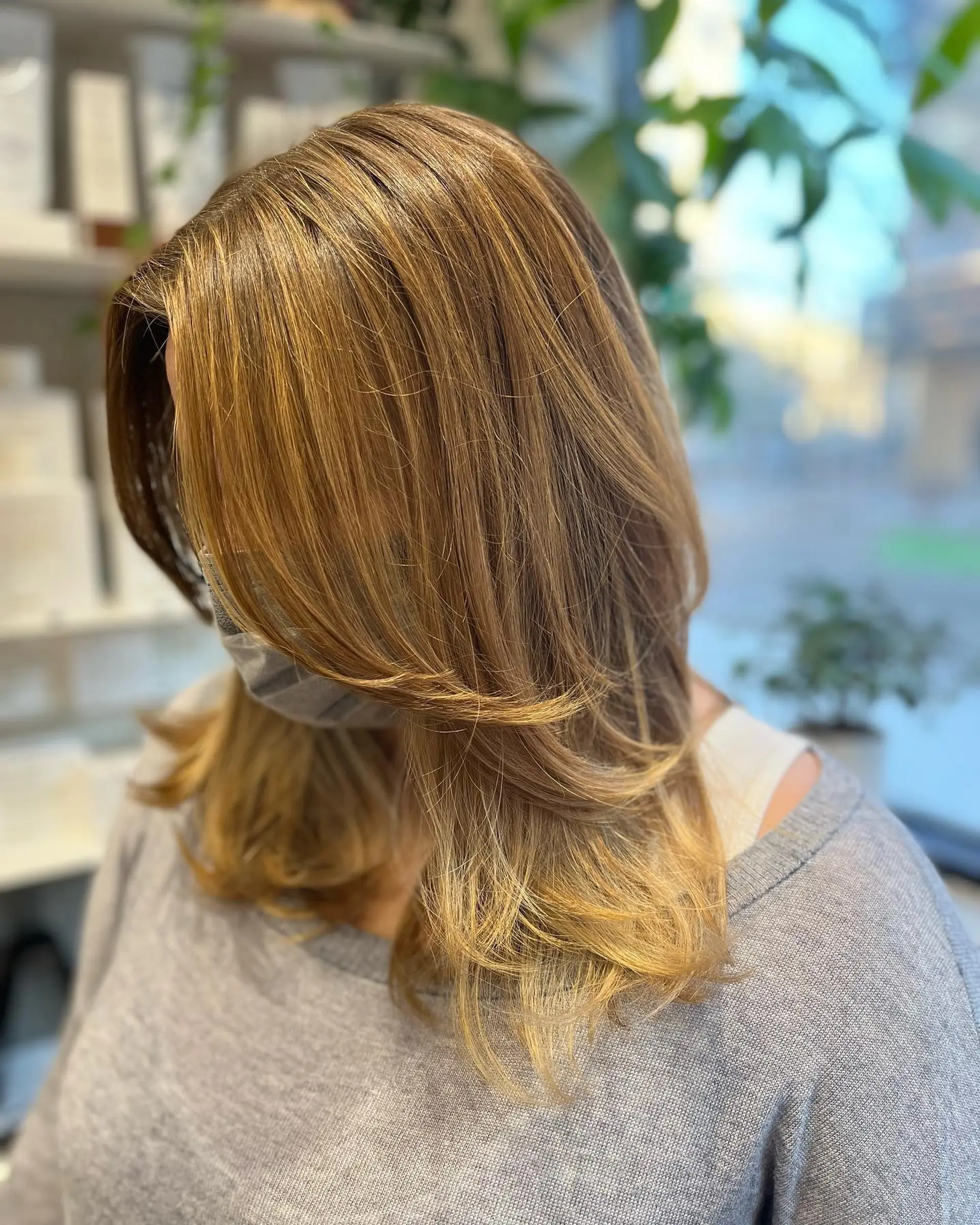 A medium-length layered haircut with caramel highlights and face-framing layers. 1
