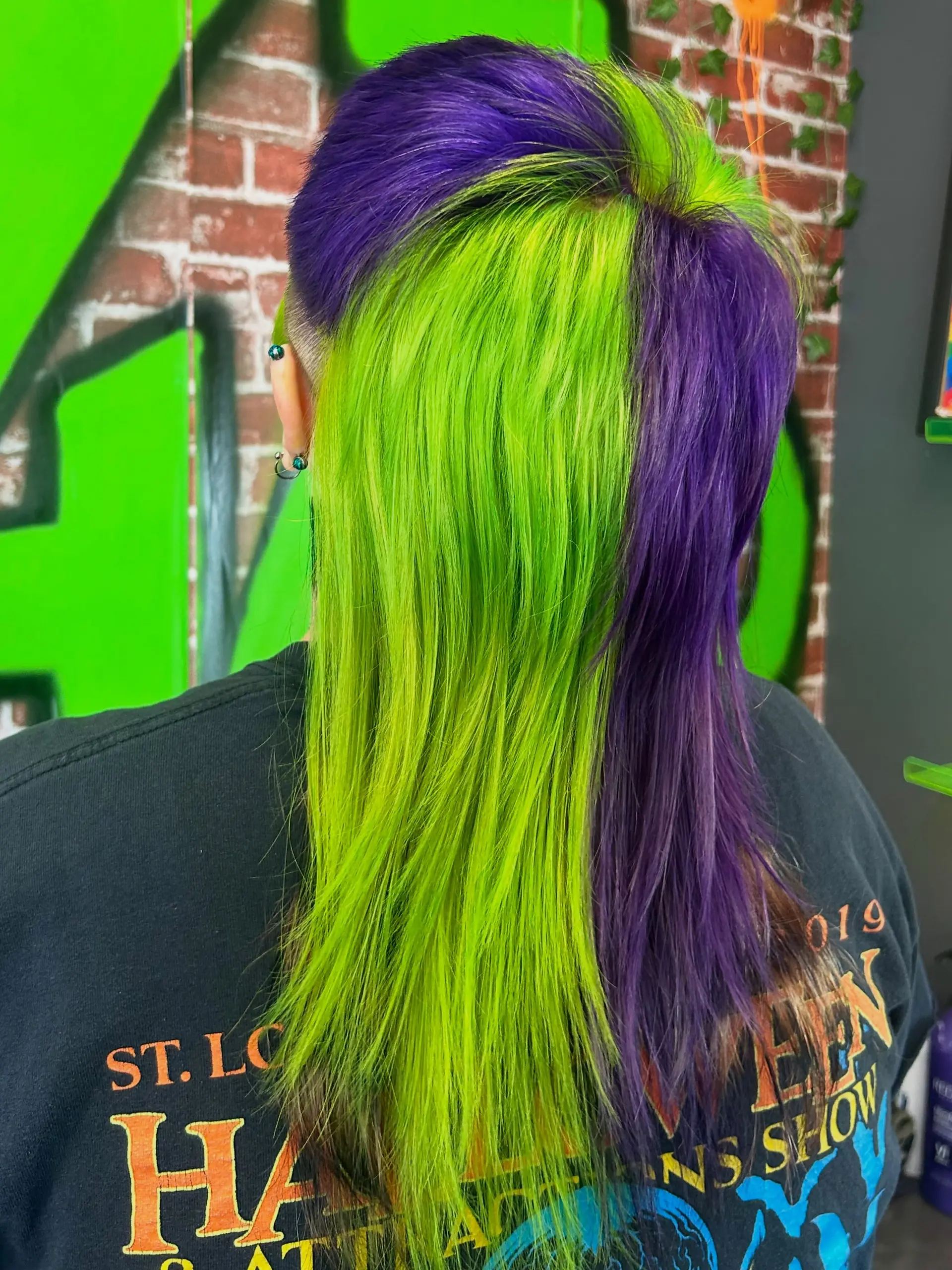 A bold alternative mullet featuring contrasting split-block panels of vivid neon lime green and deep royal purple on straight hair. 1