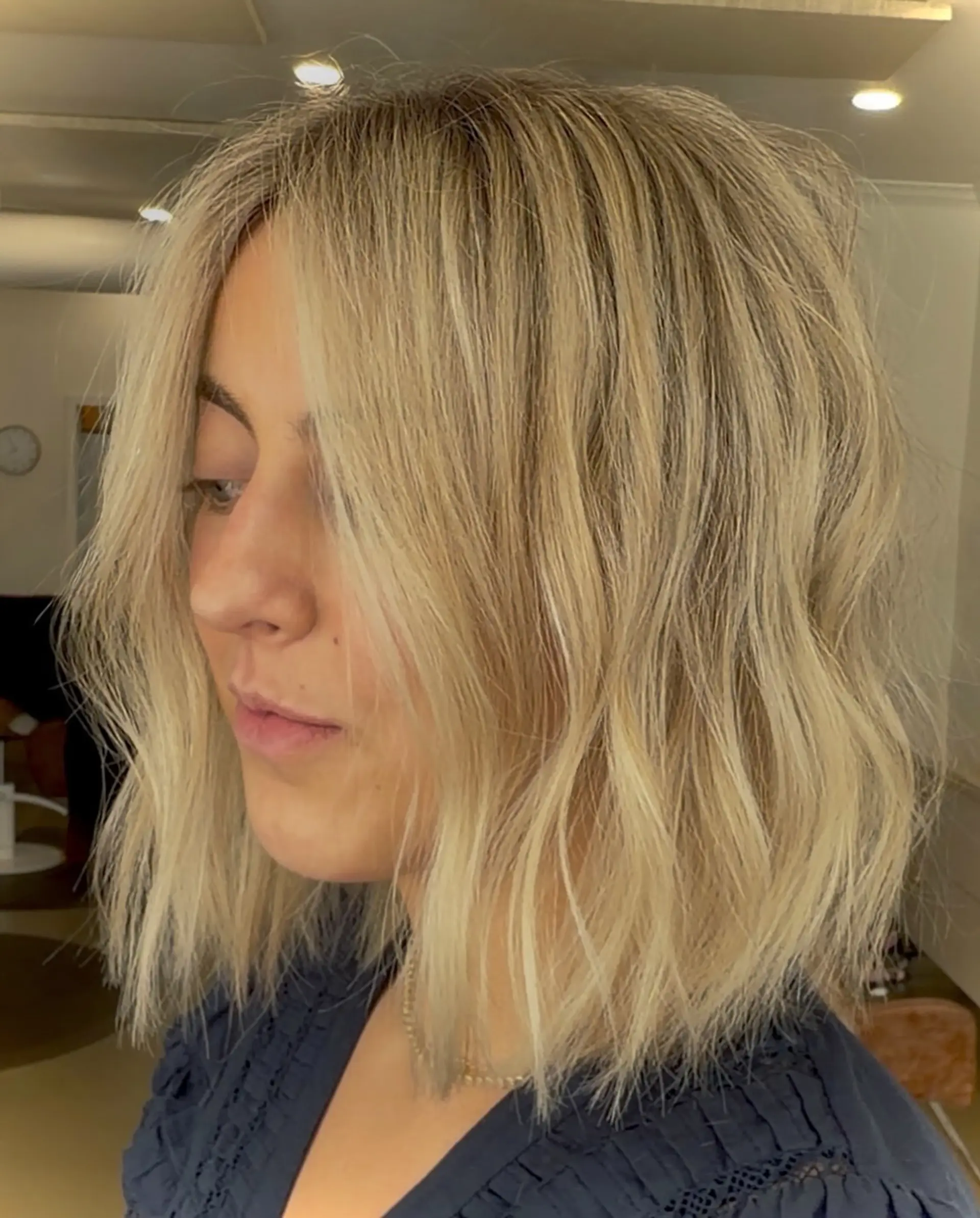 A blunt shoulder-length bob styled with tousled, textured waves and bright blonde highlights. 1