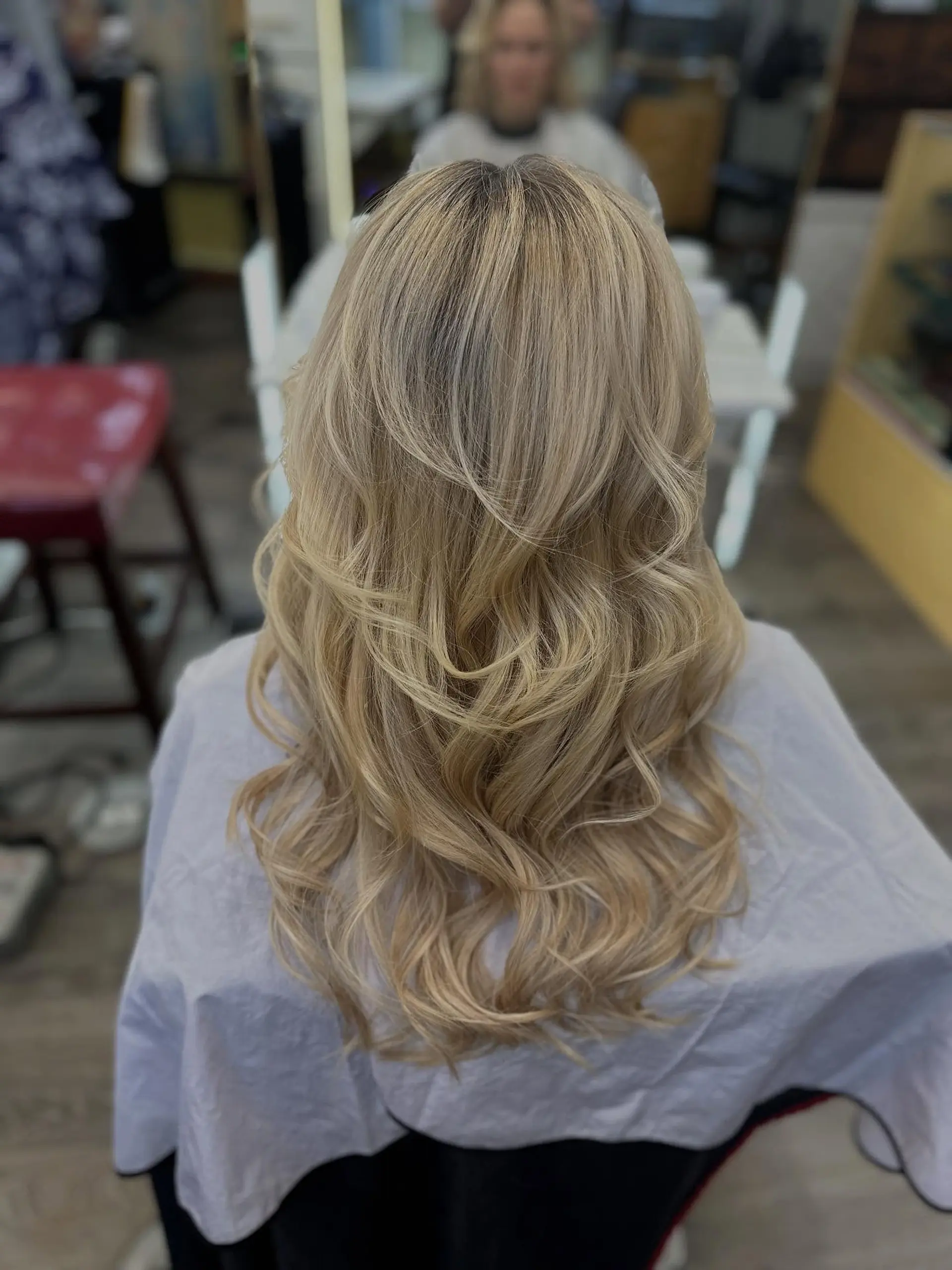 Long blonde hair styled in soft, cascading waves with dimensional layers that add body and movement. 1