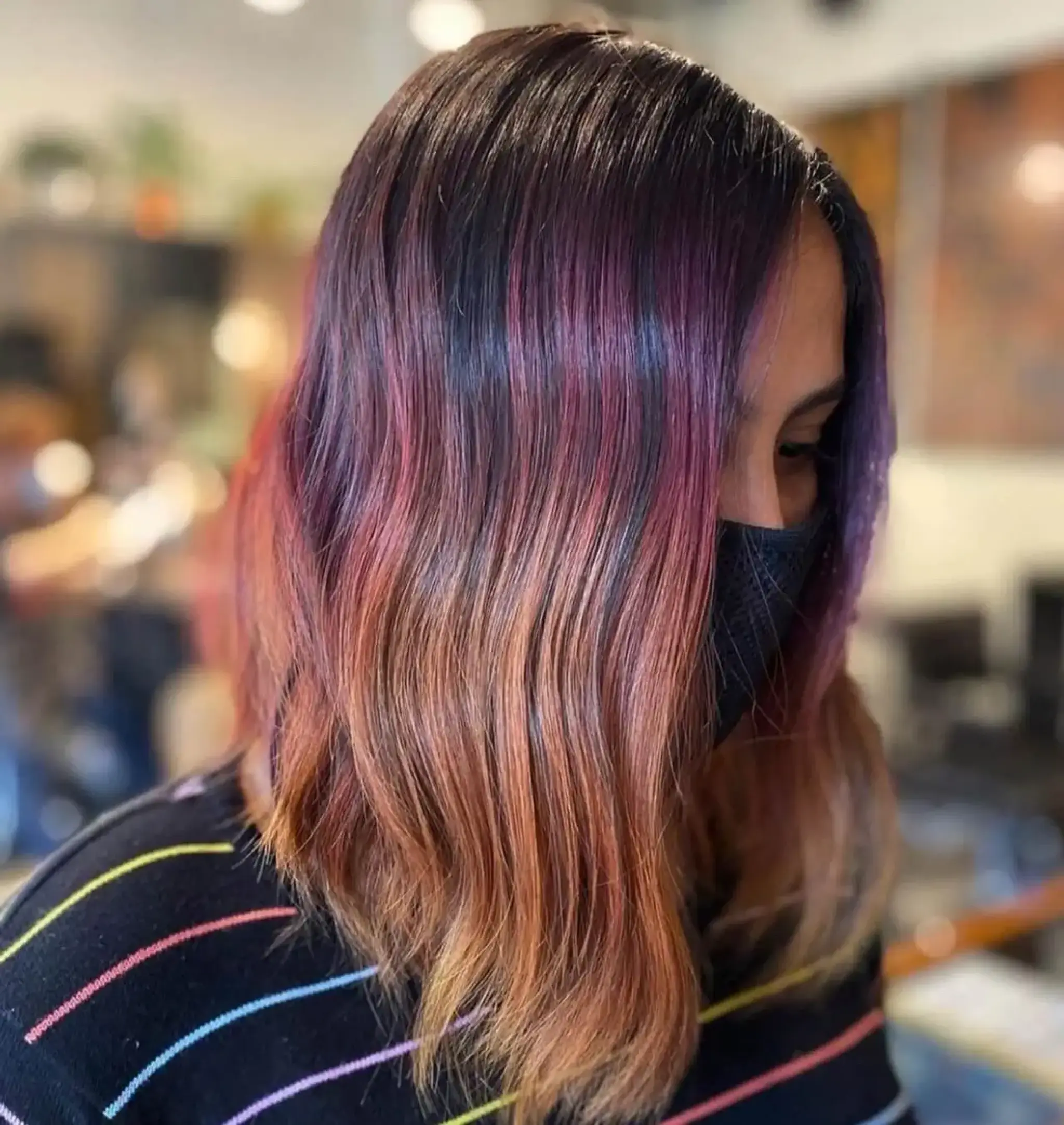 Medium-length, wavy hair displaying a beautiful ombre effect transitioning from dark brown into purple, pink, and blonde tips.